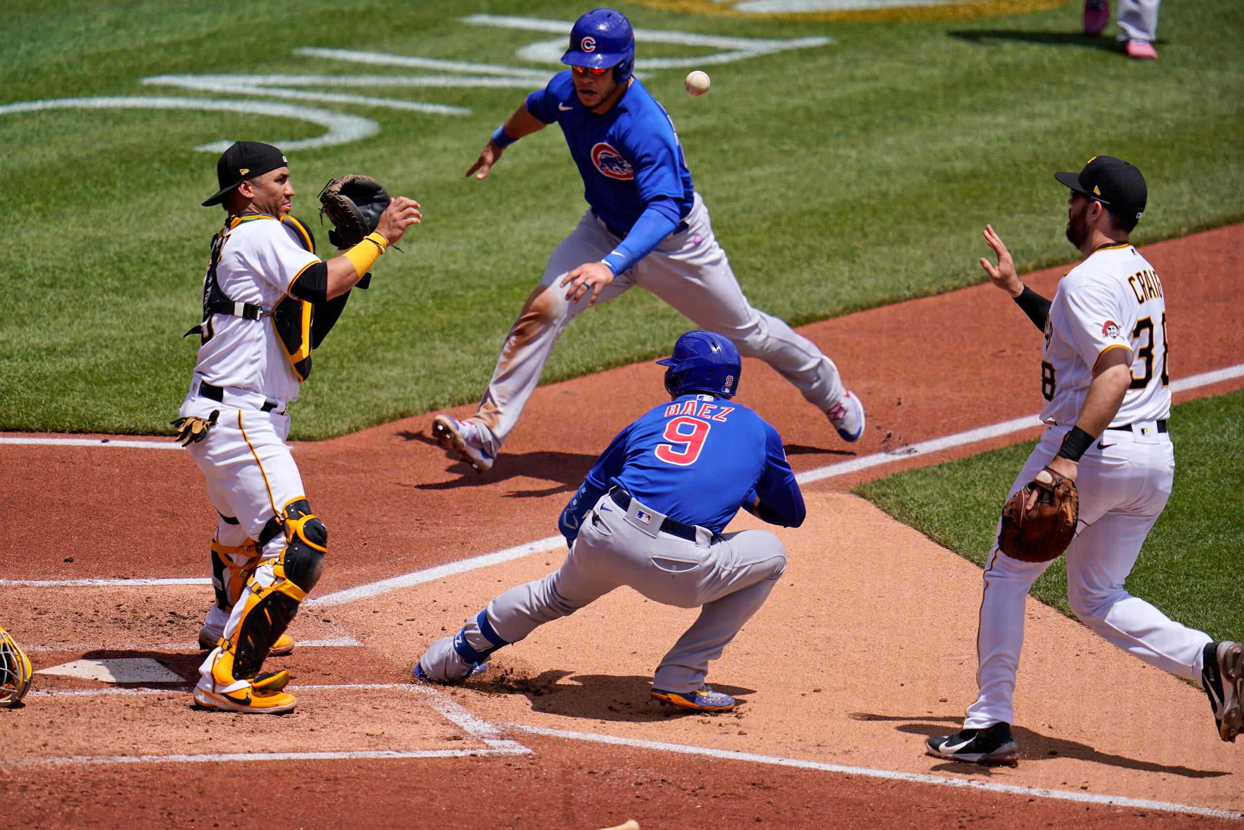 Instante en que Javier Báez (centro) regresa al 'home' luego de que casi llegara a primera base, mientras Wilson Contreras se apresta a deslizarse en el plato al tiempo que el inicialista Will Craig le pasa la pelota al receptor boricua de los Pirates, Michael Pérez.