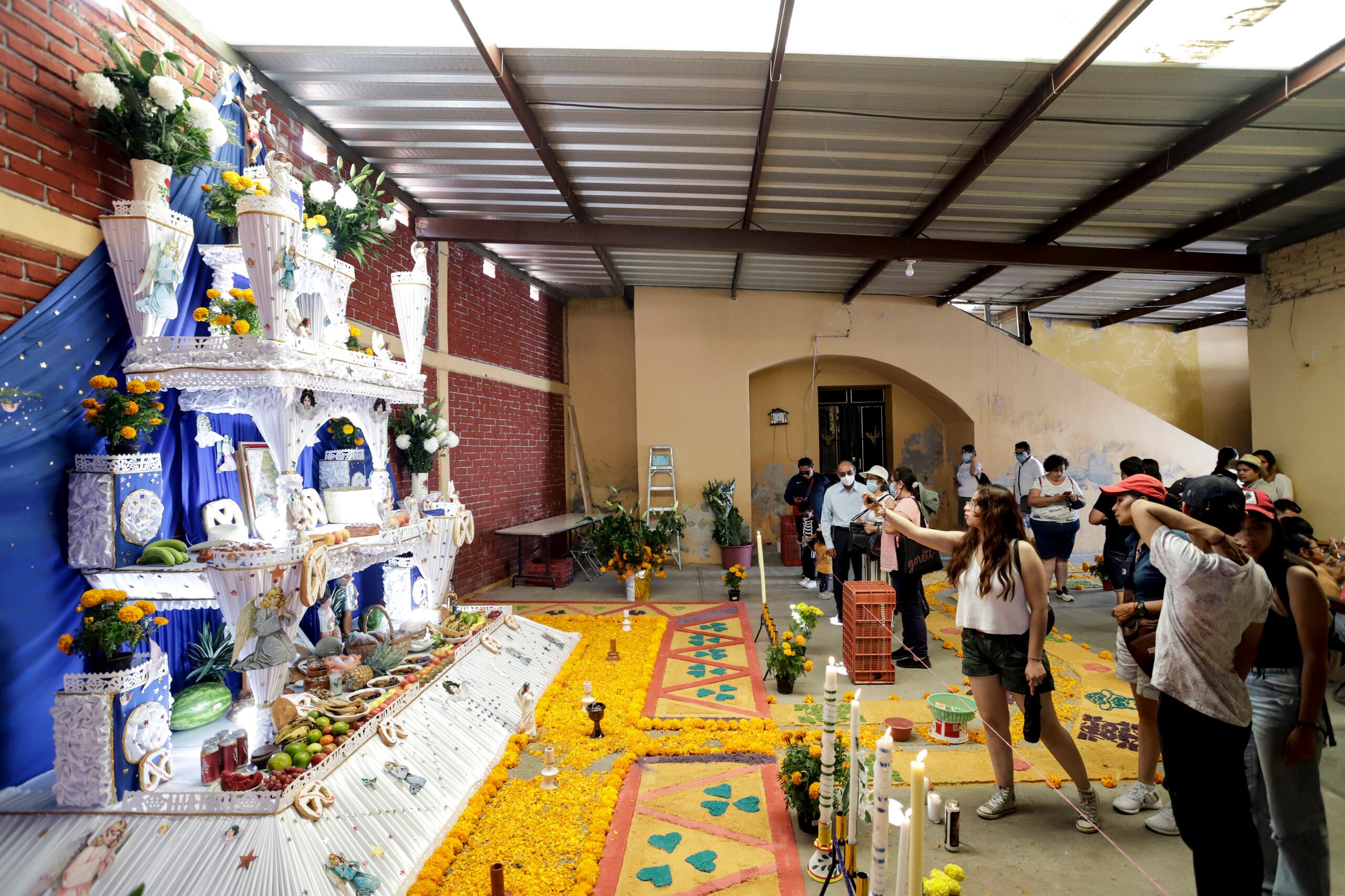 Varias personas visitan altares durante la celebración de Día de Muertos, el 1 de noviembre de 2022, en el municipio de Huaquechula, en Puebla, México. (EFE/ Hilda Ríos)