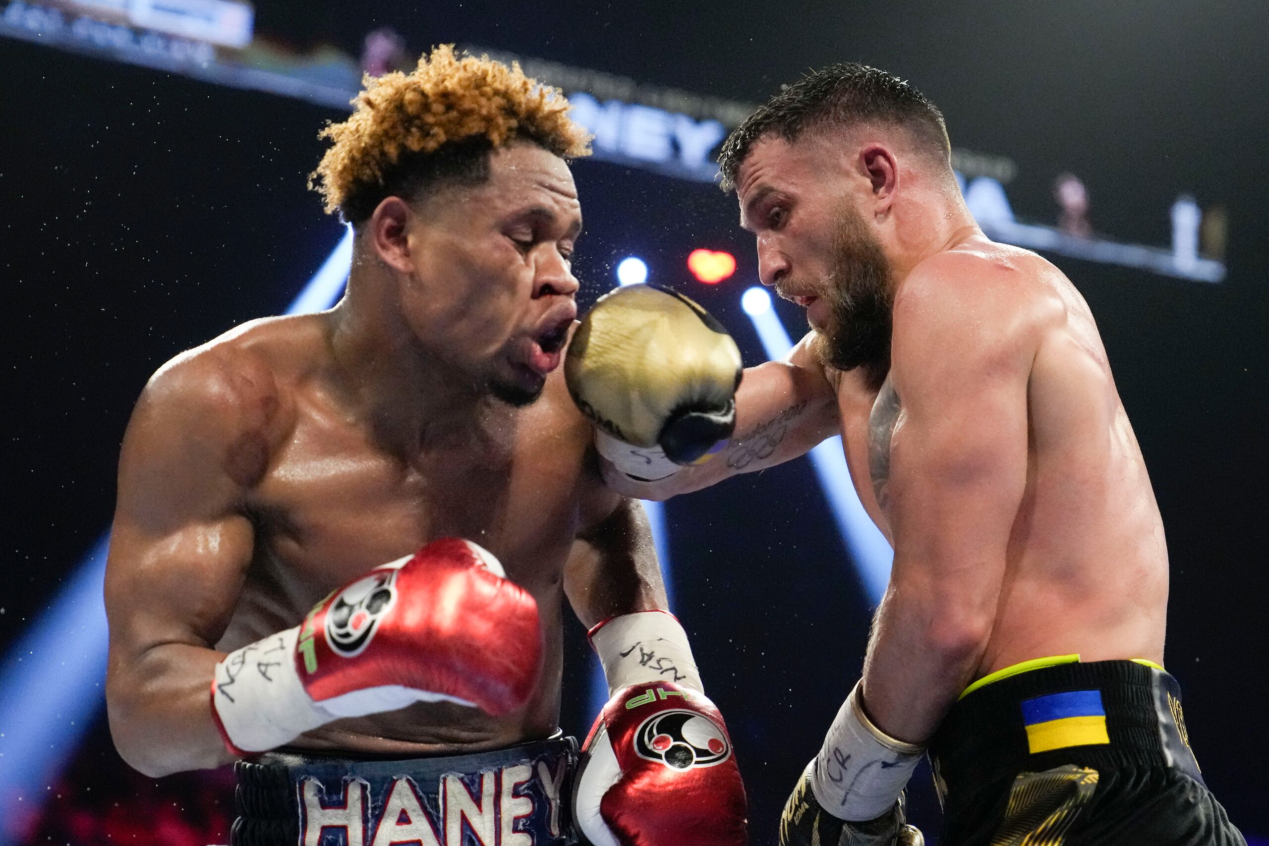 Devin Haney, izquierda, está en el cuerpo a cuerpo con Vasiliy Lomachenko en la pelea de los pesos ligeros en Las Vegas el sábado en la noche.