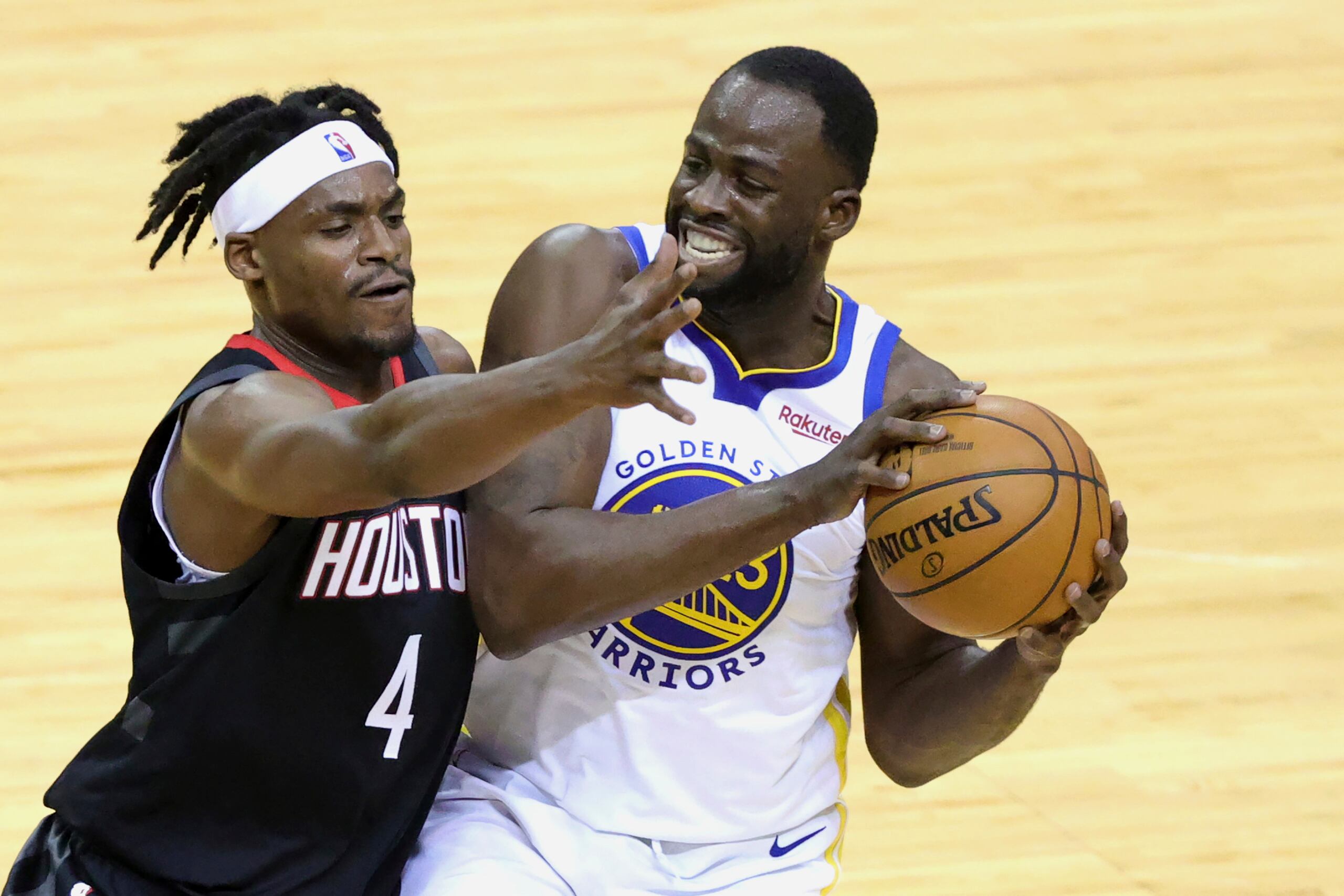 Draymond Green, de los Warriors, evita que Danuel House Jr., de los Rockets, le quite el balón.