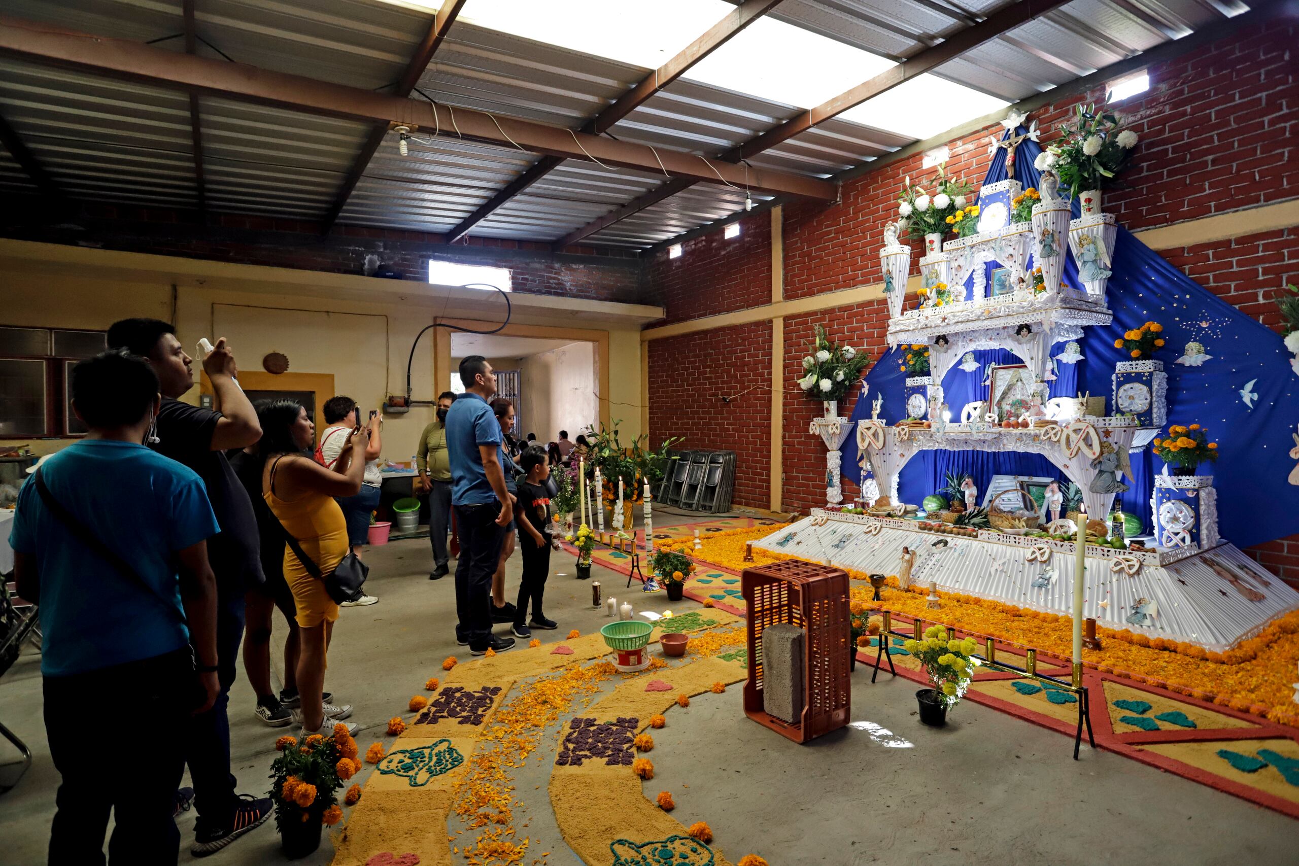 Varias personas visitan altares durante la celebración de Día de Muertos, el 1 de noviembre de 2022, en el municipio de Huaquechula, en Puebla, México. (EFE/ Hilda Ríos)