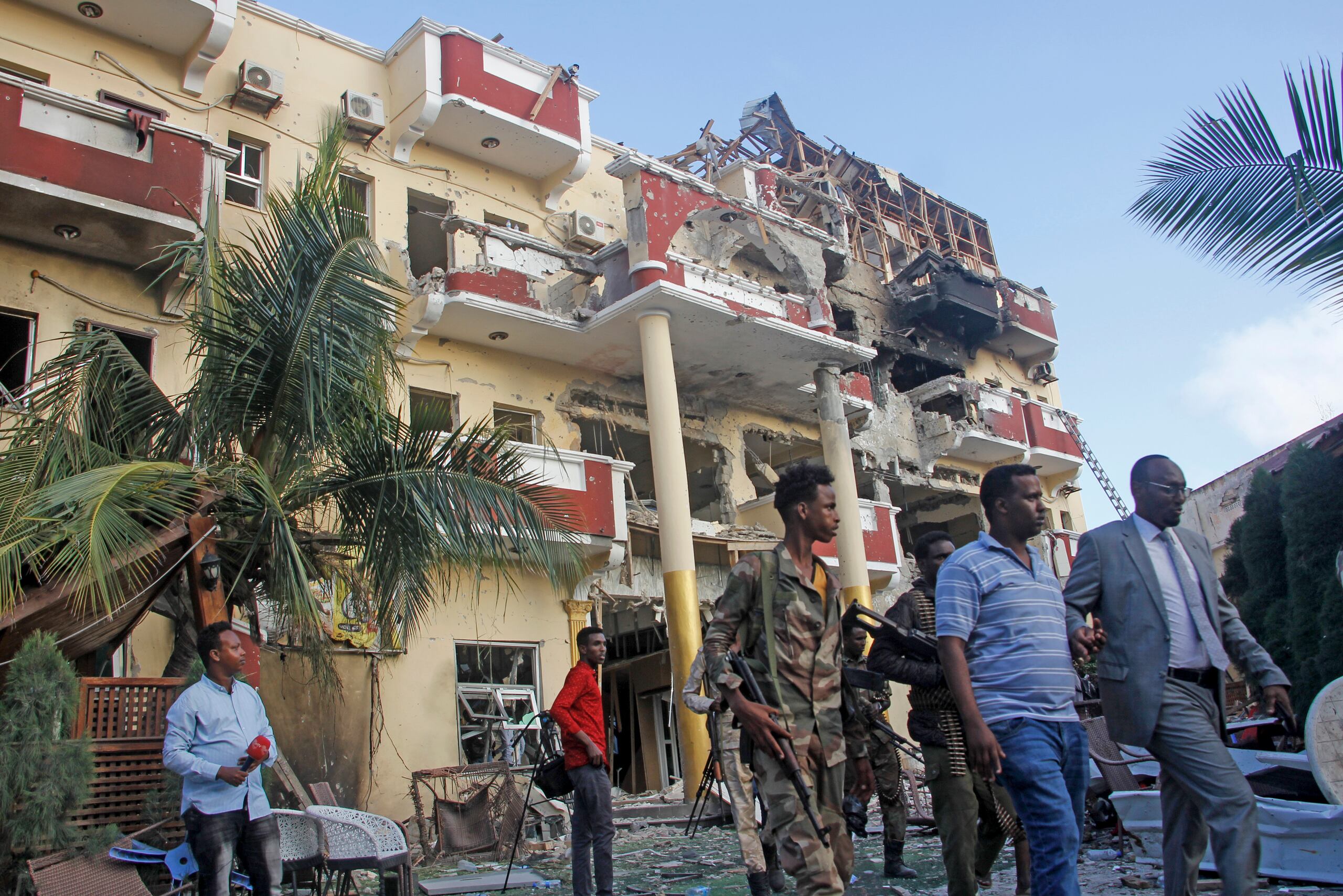 Elementos de seguridad y otras personas caminan frente al dañado Hotel Hayat en Mogadiscio, capital de Somalia.