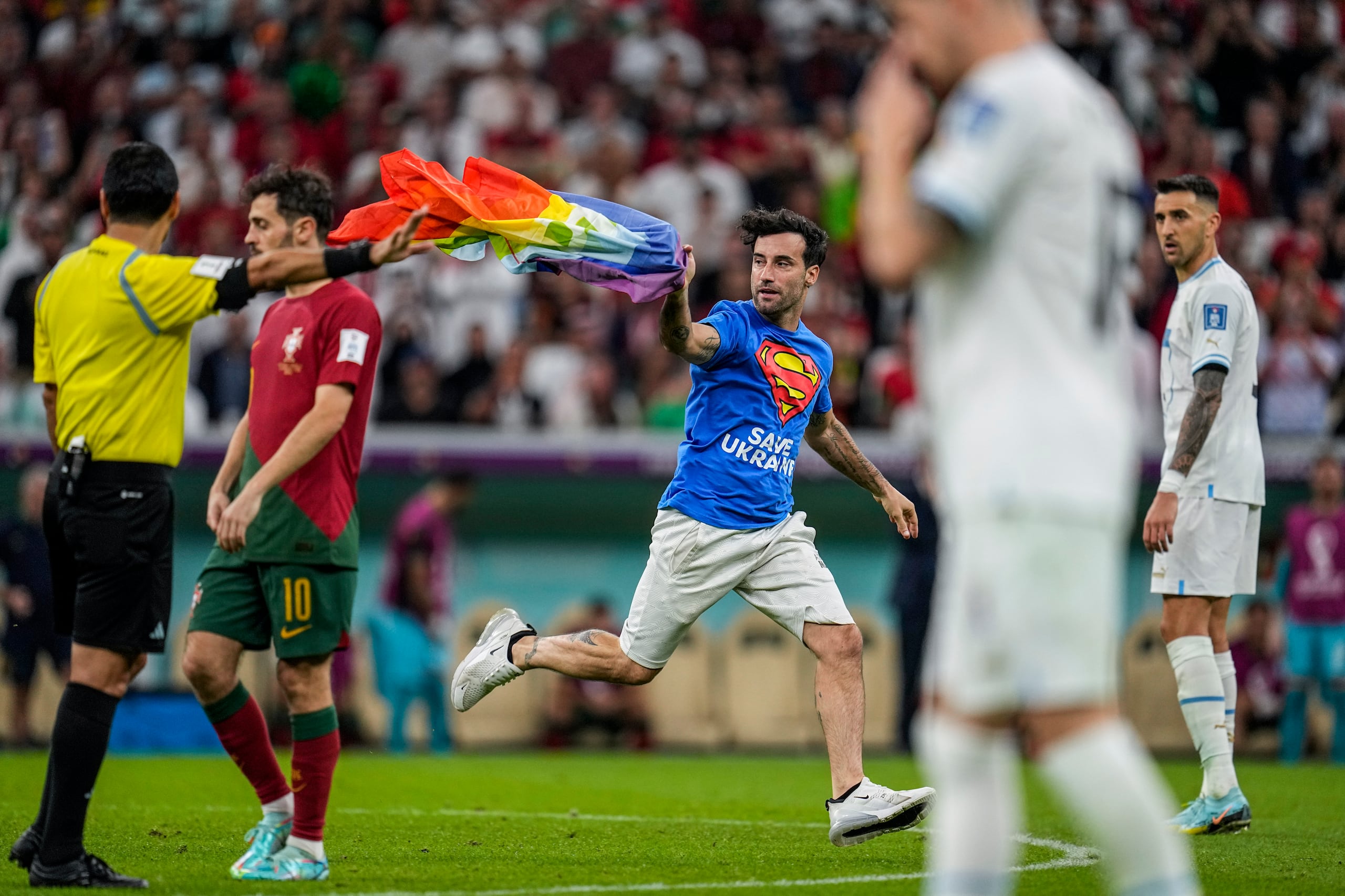 Un aficionado irrumpió en la cancha con la bandera arcoíris durante el partido del Grupo H entre Portugal y Uruguay, el lunes 28 de noviembre de 2022, en Lusail, Qatar.