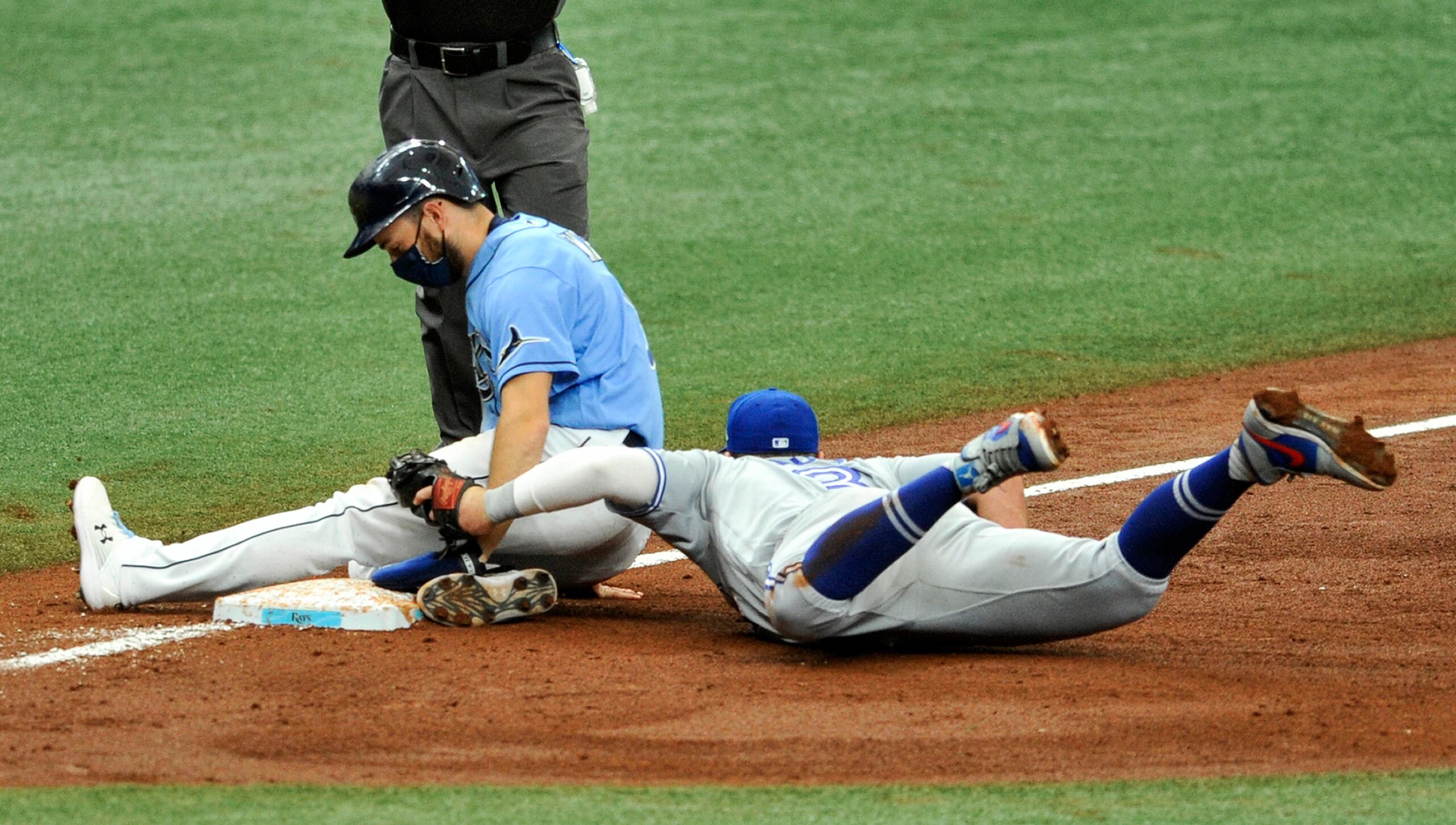 Brandon Lowe, de los Tays de Tampa Bay, a la izquierda, consigue llegar a salvo a tercera pese al esfuerzo de Brandon Drury, de los Azulejos de Toronto, durante el partido del domingo.