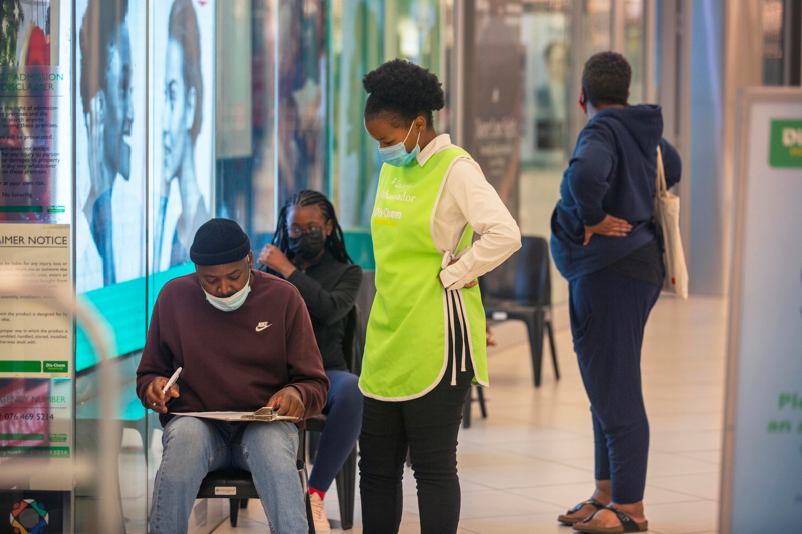 Varias personas esperan para vacunarse contra el COVID-19 en un centro comercial en Johannesburgo, Sudáfrica, donde una nueva variante del virus comienza a causar preocupación.