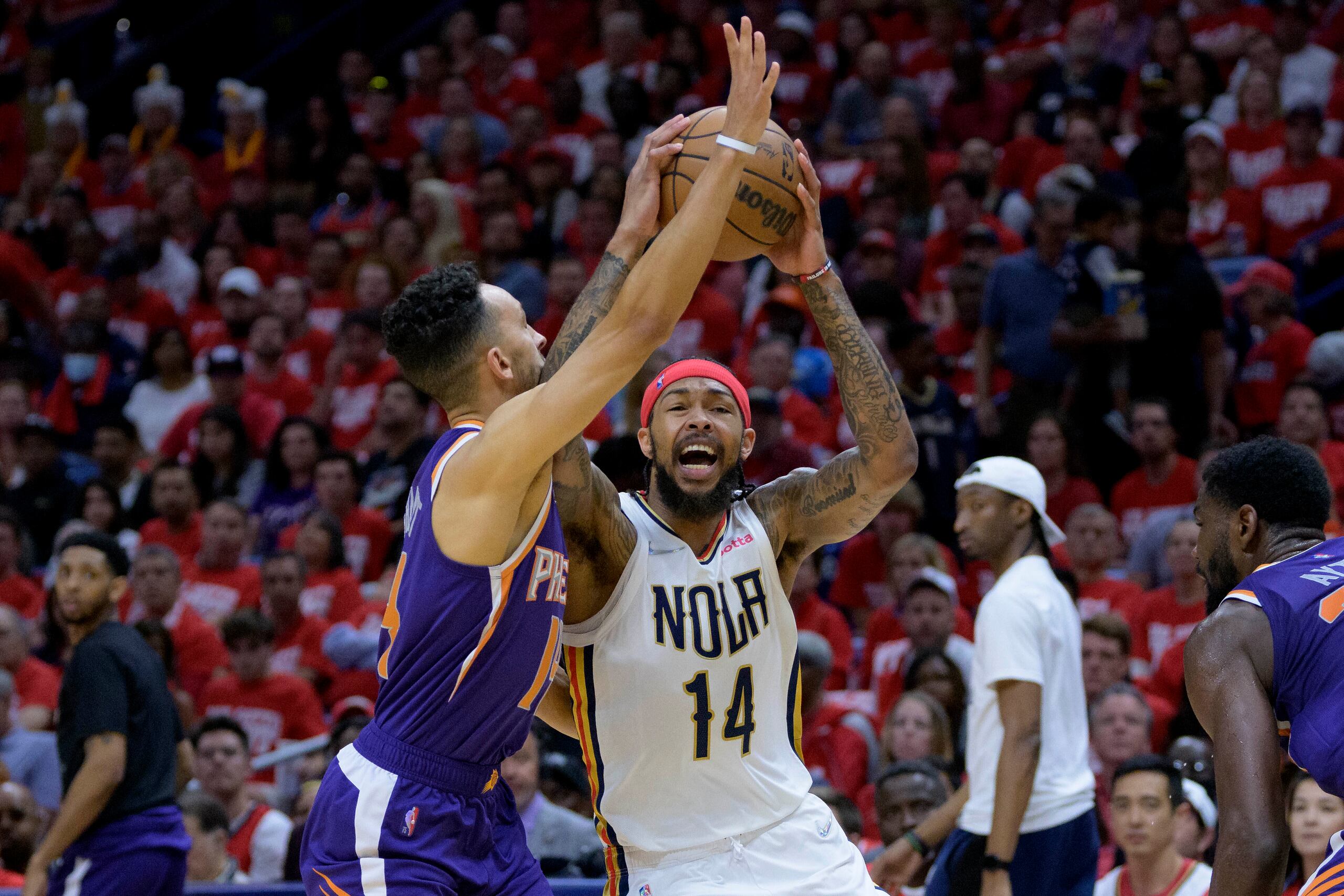 El jugador de los Pelicans de Nueva Orleans Brandon Ingram (con el 14) trata de lanzar el balón ante el jugador de los Suns de Phoenix Landry Shamet en la primera mitad del cuarto partido de su serie de primera ronda de playoffs en Nueva Orleans, el domingo 24 de abril de 2022. (AP Foto/Matthew Hinton)