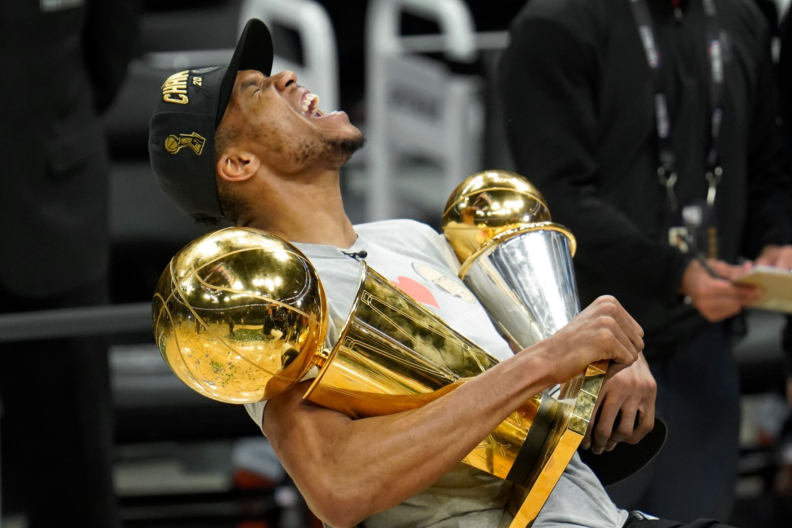 Antetokounmpo grita de alegría con los trofeos de campeonato de la NBA y Jugador Más Valioso de las Finales.