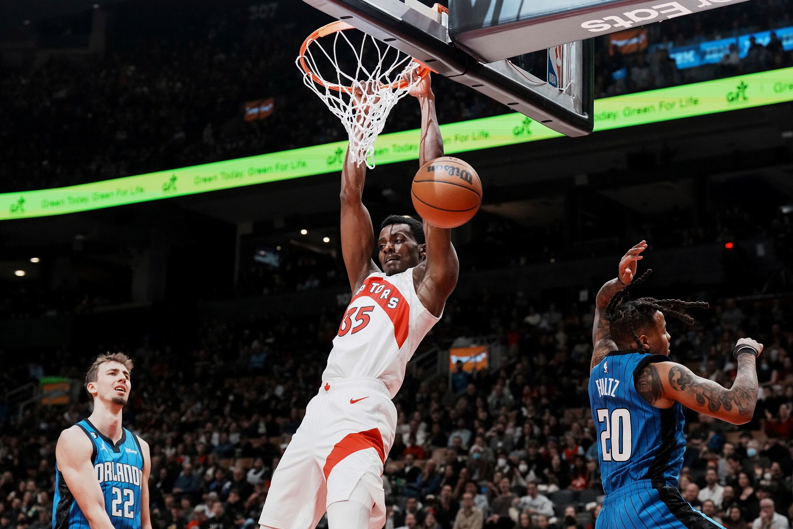 Christian Koloko, de los Raptors de Toronto, donquea el balón frente a Franz Wagner (22) y Markelle Fultz, del Magic de Orlando, en el encuentro del sábado.