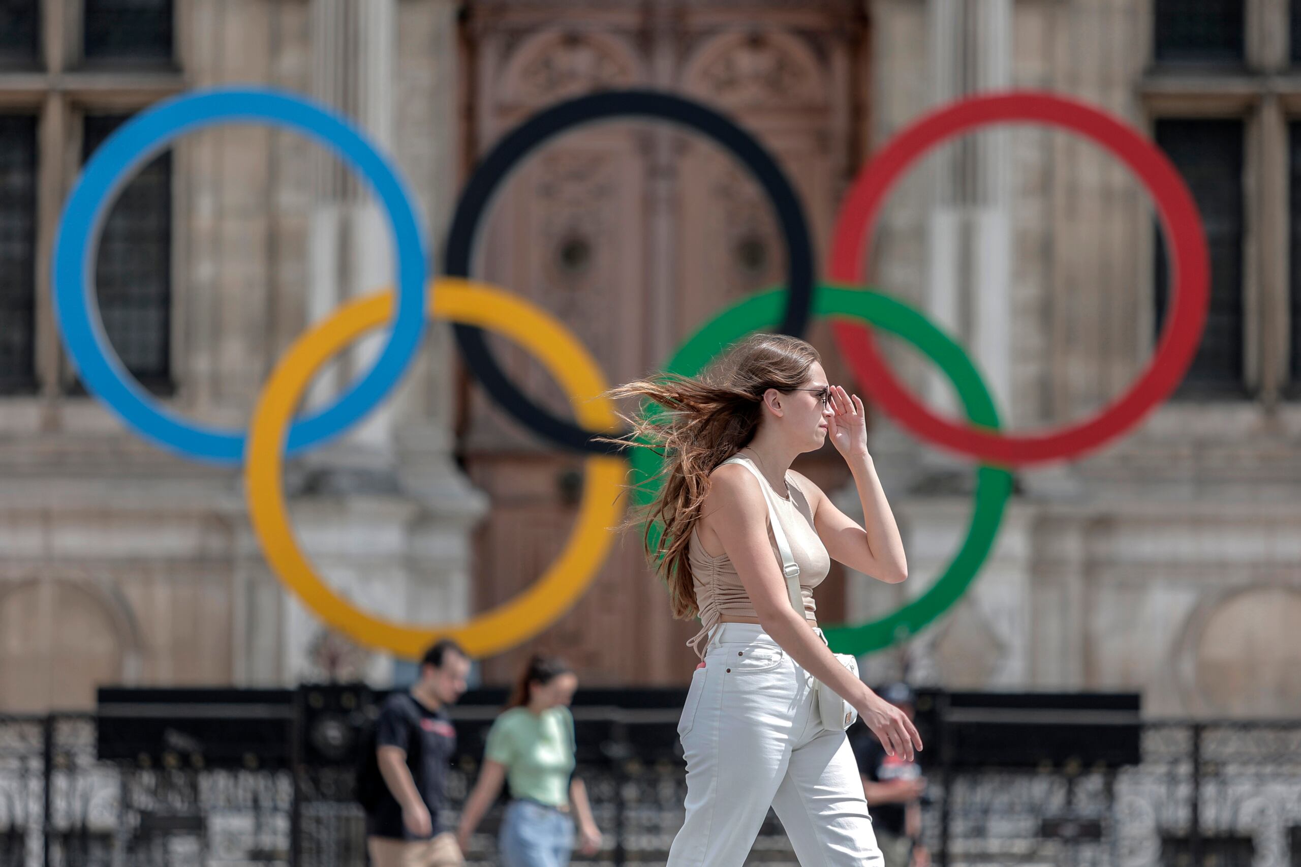 En esta foto del 25 de julio del 2022, una mujer pasa junto a los aros olímpicos afuera del ayuntamiento de París.