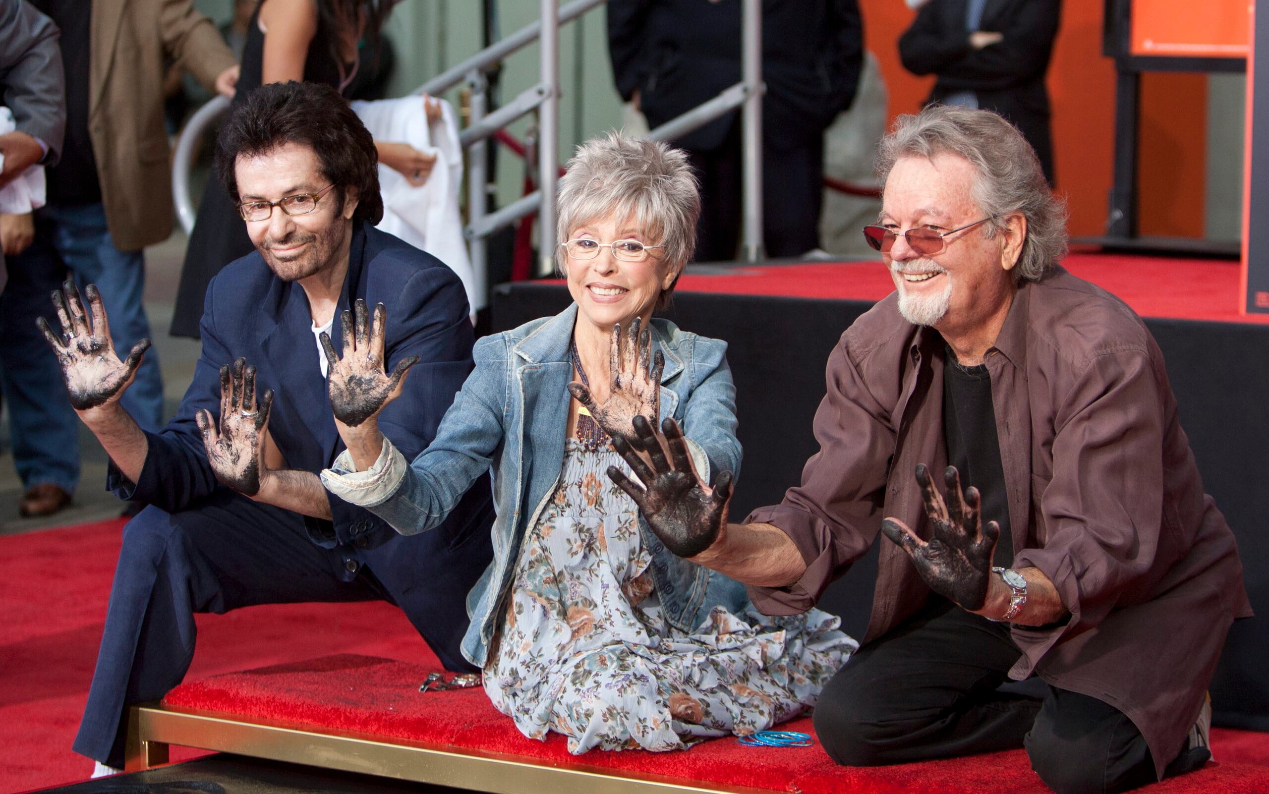 Los actores protagonistas del célebre musical "West Side Story", ganador de 10  premios Óscar, George Chakiris (i.), Rita Moreno (c) y Russ Tamblyn (d.), muestran sus manos después de registar en cemento sus nombres, sus manos y sus pies, en el Teatro Chino de Hollywood, California.