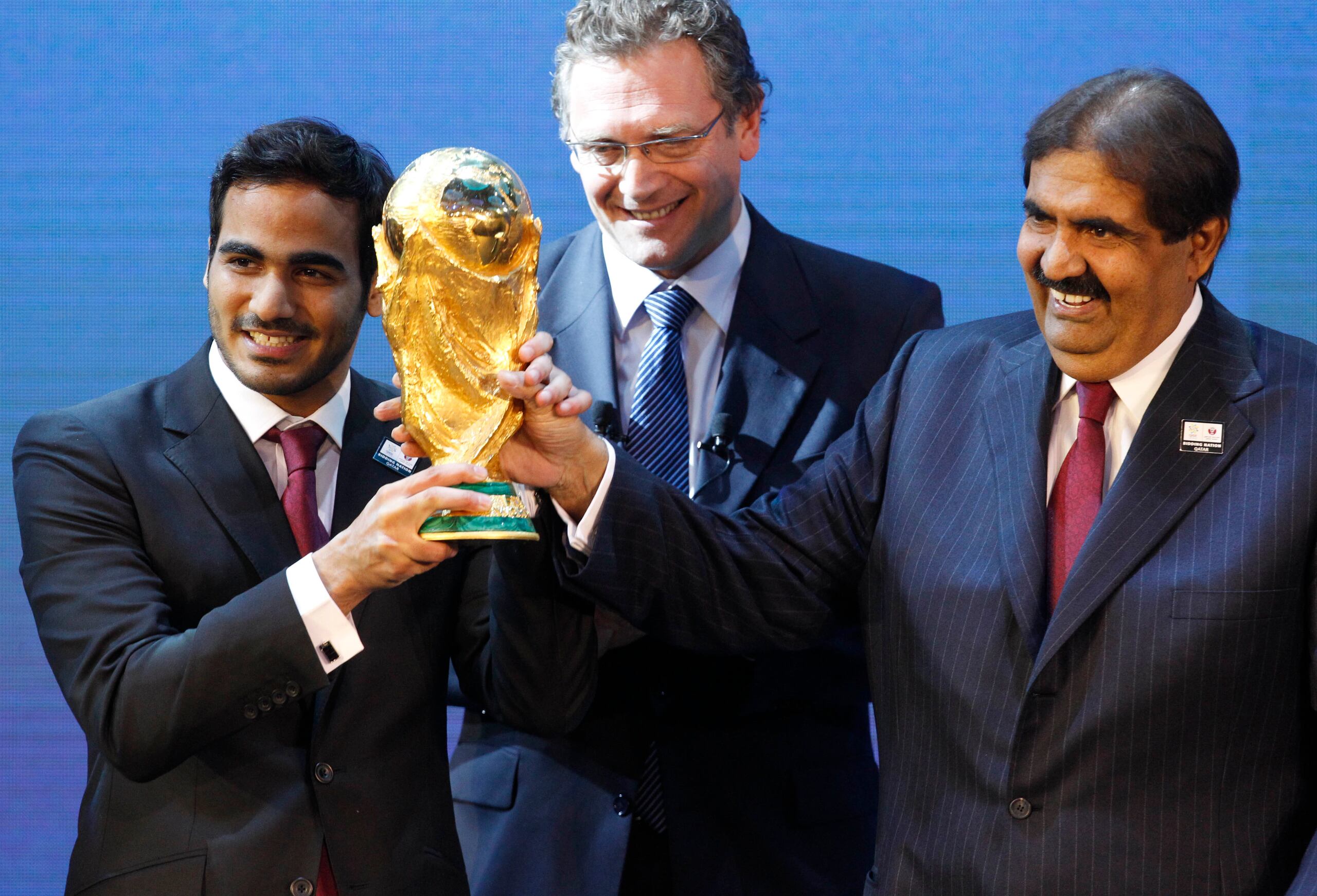 En esta foto del 2010, Mohamed bin Hamad Al-Thani, presidente del comité organizador, a la izquierda, y el Sheikh Hamad bin Khalifa Al-Thani, Emir de Catar, a la derecha, sonríen junto al exsecretario general de la FIFA, Jerome Valcke, luego de que se le otorgara a Catar la sede del Mundial FIFA del 2022.