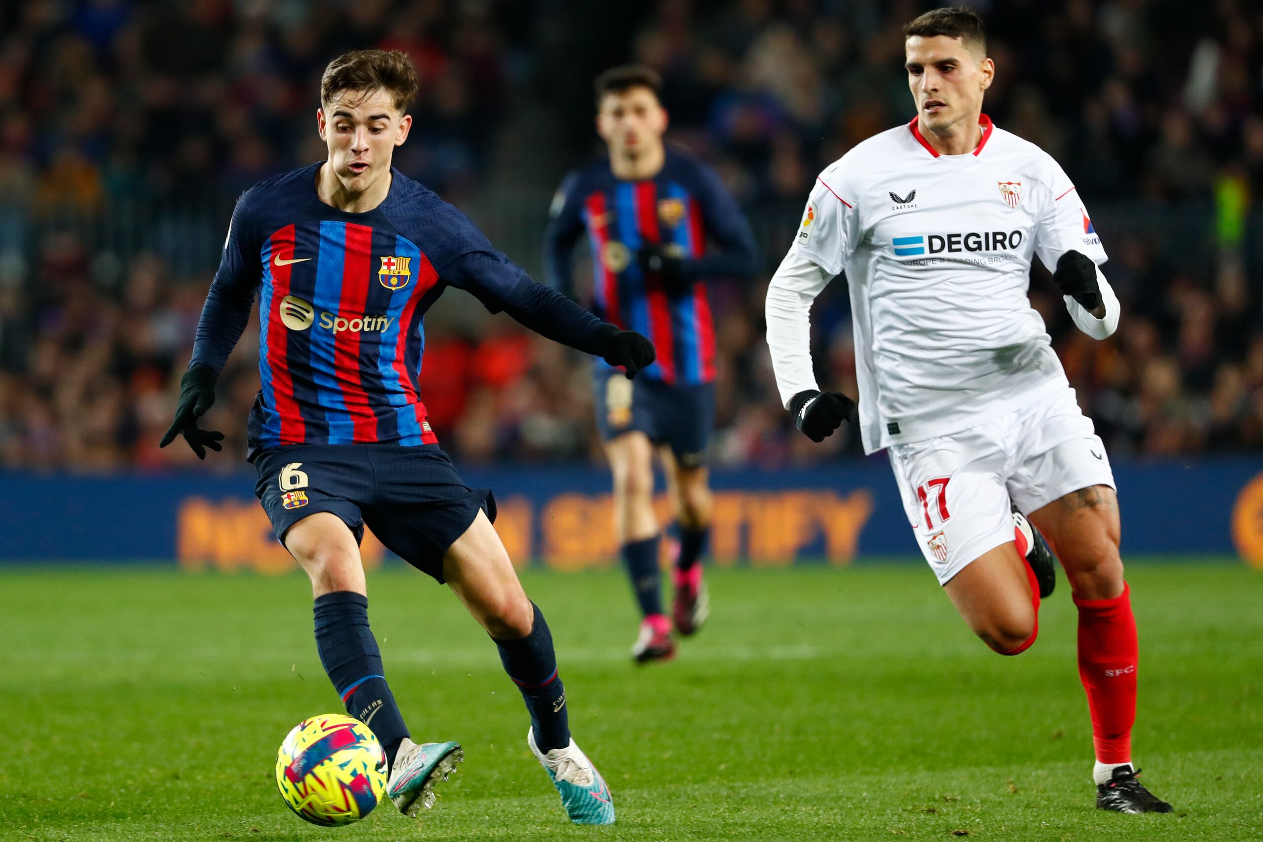 Gavi, izquierda, del Barcelona, avanza ante Erik Lamela, del Sevilla, durante un juego de la Liga española, en el Camp Nou de Barcelona, el domingo 5 de febrero de 2023. (AP Foto/Joan Monfort)