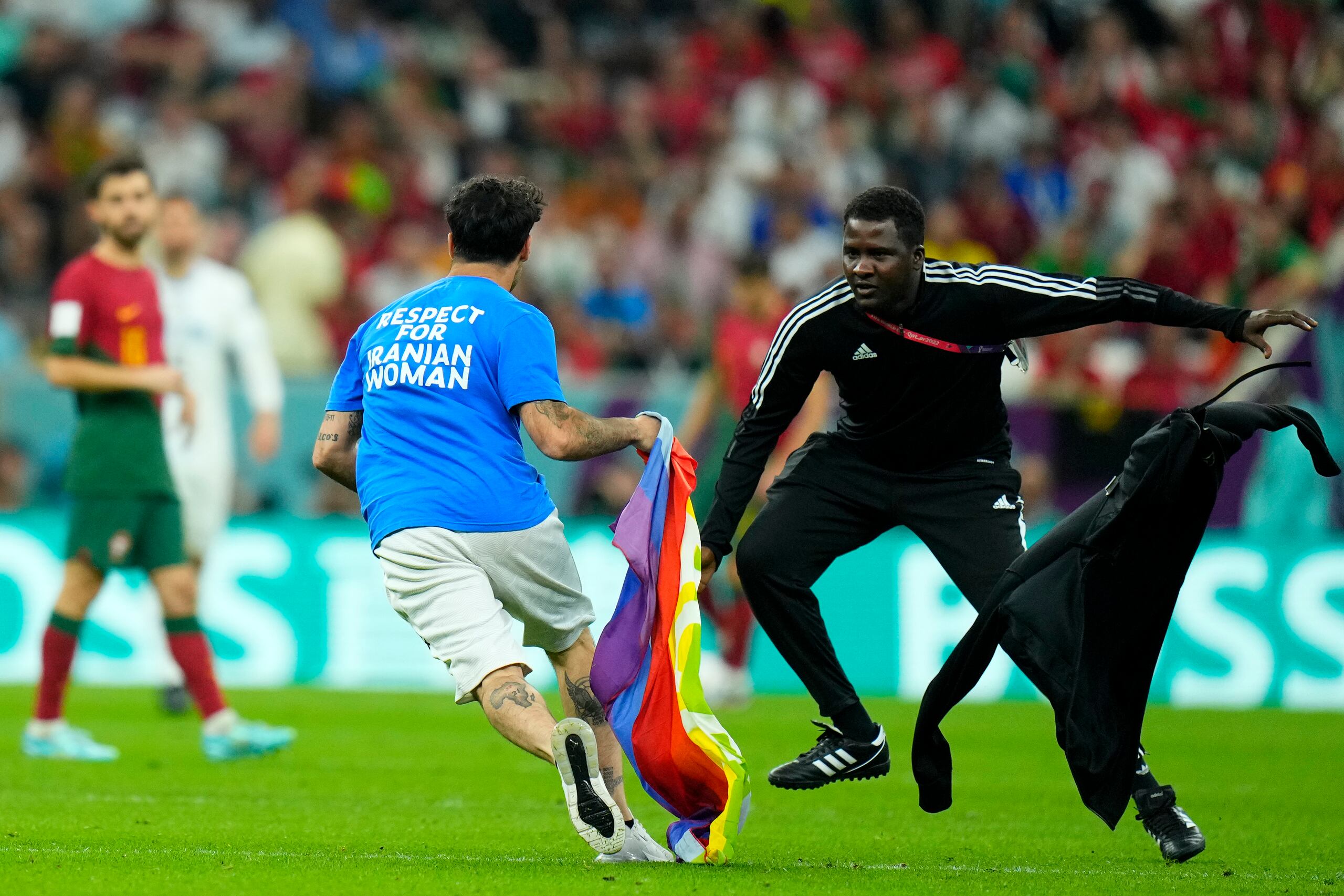 Un aficionado es perseguido tras irrumpir en la cancha con la bandera arcoíris durante el partido del Grupo H entre Portugal y Uruguay, el lunes 28 de noviembre de 2022, en Lusail, Qatar. (AP Foto/Petr David Josek)