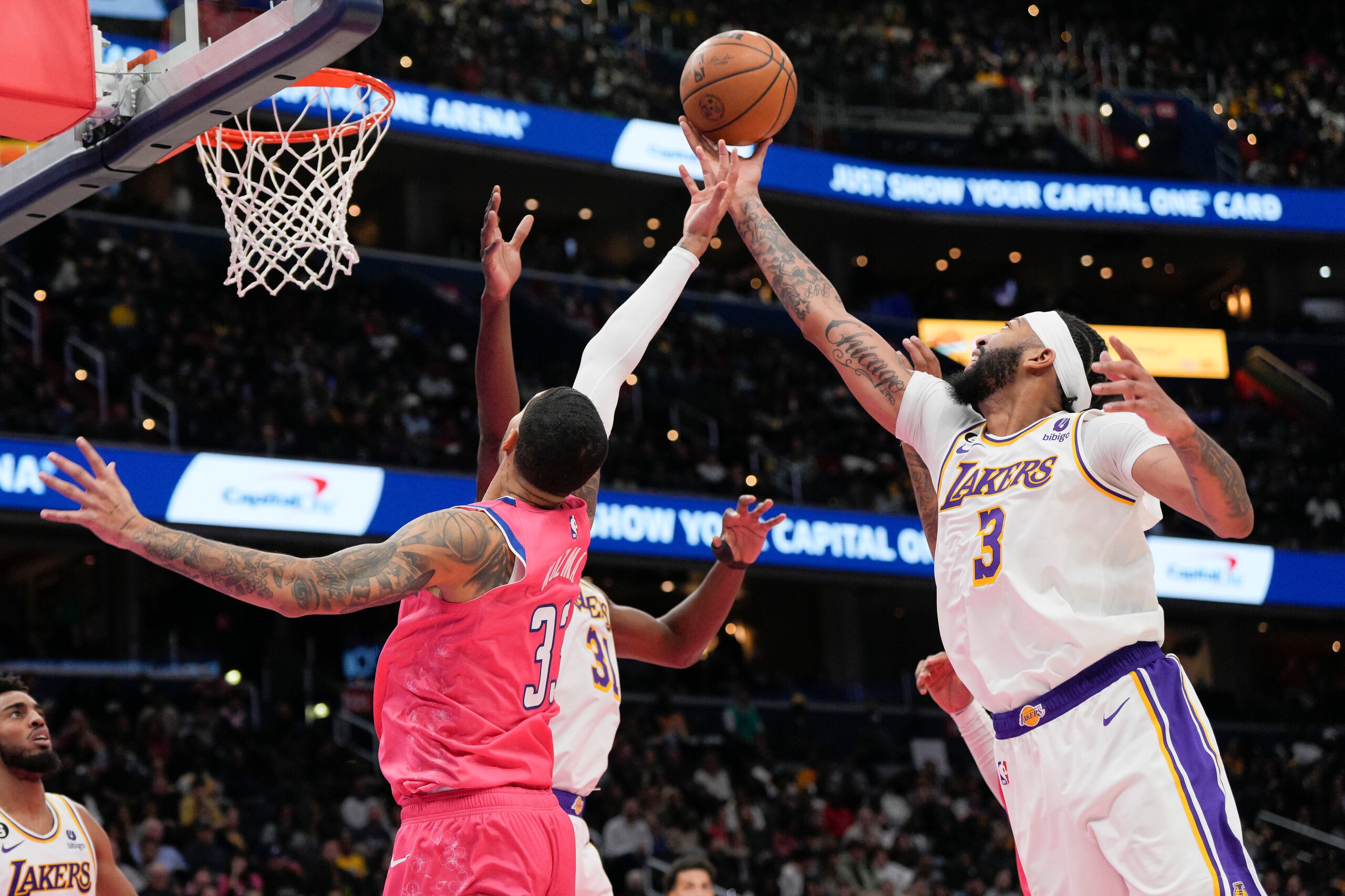 El alero de los Wizards de Washington Kyle Kuzma y el alero de los Lakers de Los Ángeles Anthony Davis estiran el brazo para alcanzar un rebote en el encuentro del domingo 4 de diciembre del 2022. (AP Foto/Jess Rapfogel)