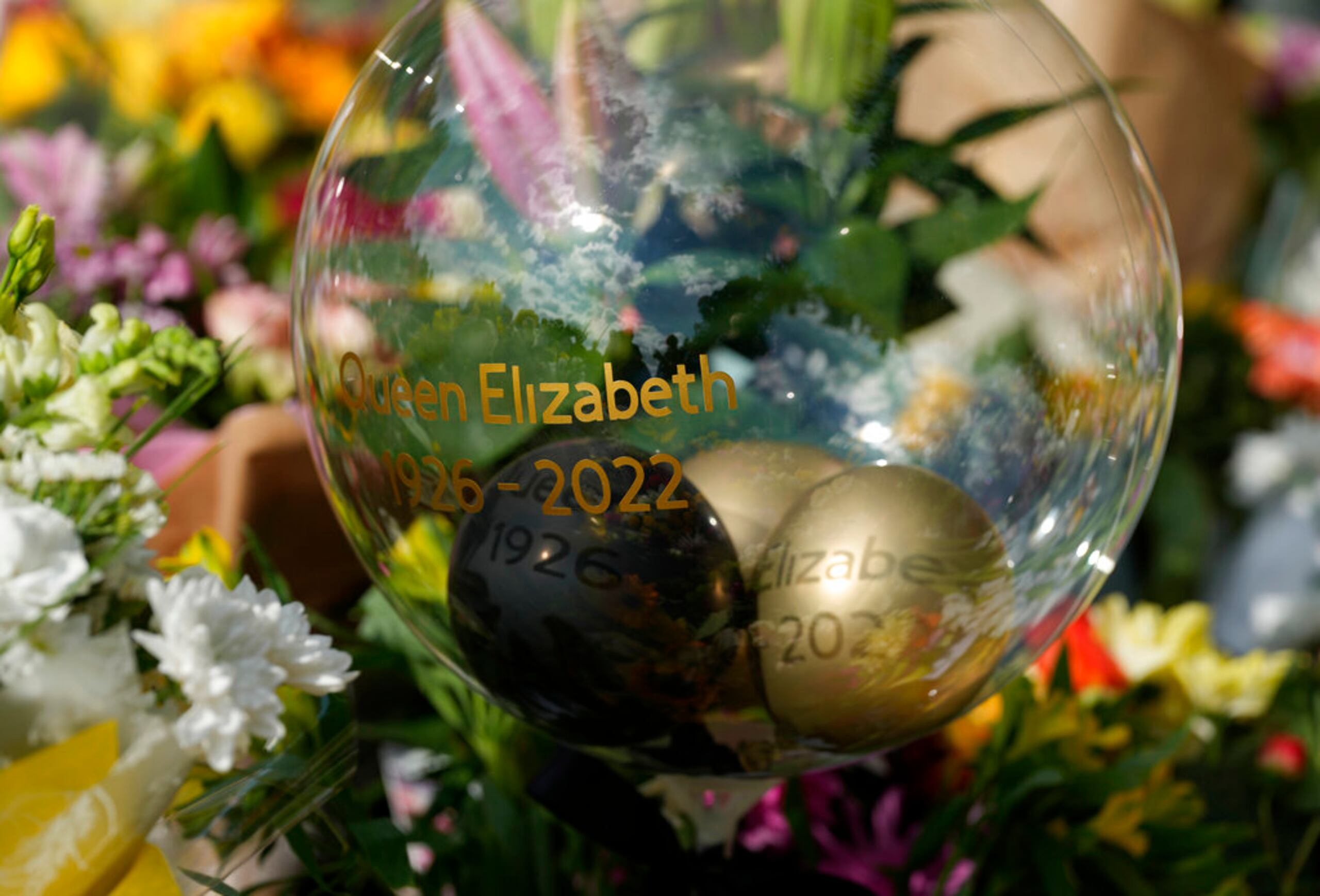 Una bola de cristal y tributos florales a la reina Isabel II frente a las puertas del Castillo de Windsor en Windsor, Inglaterra, el viernes 9 de septiembre de 2022. La reina Isabel II, la monarca con el reinado más largo de Gran Bretaña y una roca de estabilidad en gran parte de un turbulento siglo, murió el jueves después de 70 años en el trono. Tenía 96 años. (Foto AP/Frank Augstein)