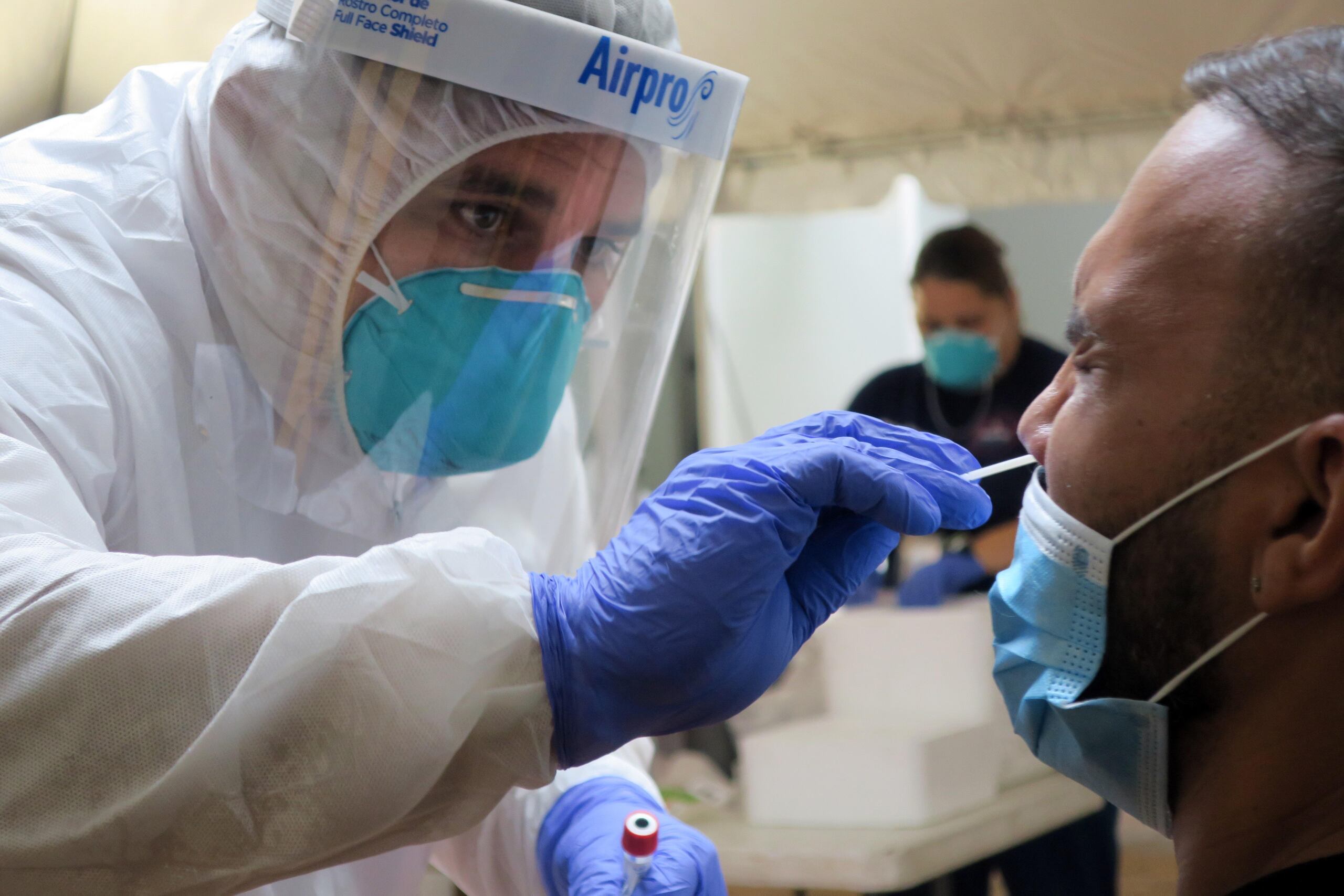 Un técnico de laboratorio inserta un hisopo en la nariz de un residente para la prueba del coronavirus en San Juan.