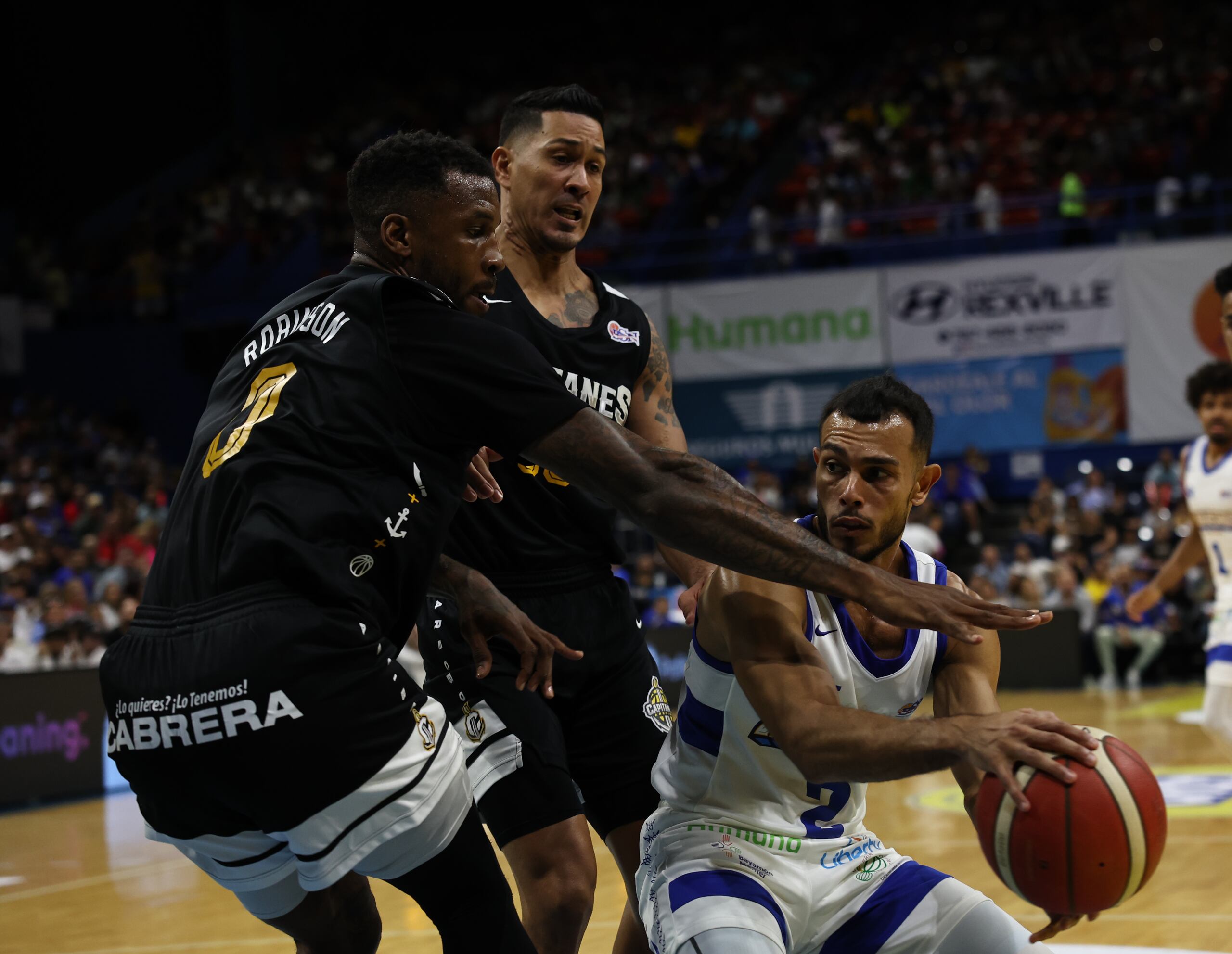 El armador de los Vaqueros de Bayamón, Javier González, queda atrapado ante la defensa de Thomas Robinson (0) y David Huertas, de los Capitanes de Arecibo, durante el encuentro del miércoles en el Rubén Rodriguez.