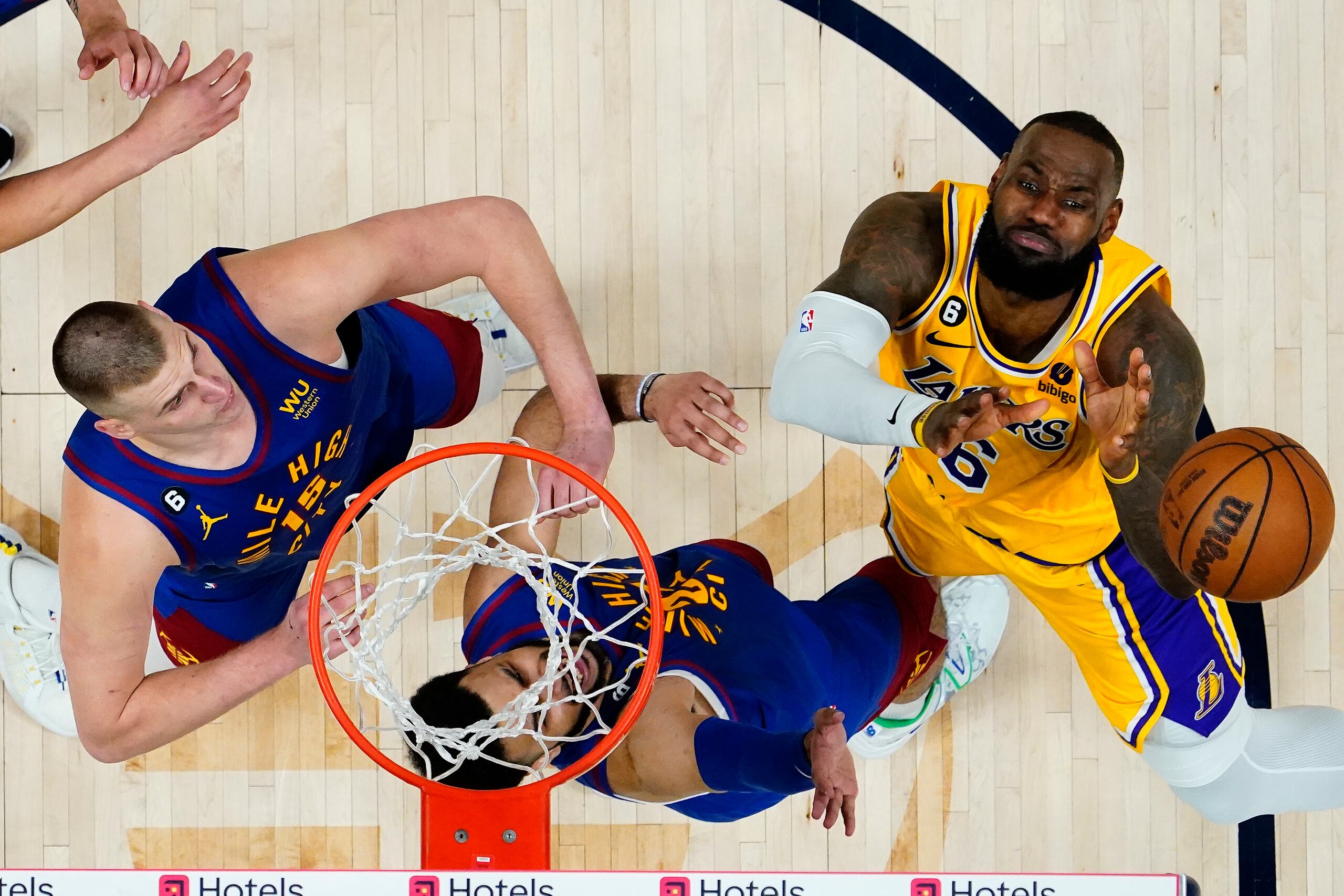 Nikola Jokic (15) y Jamal Murray intentan detener una penetración de LeBron James.