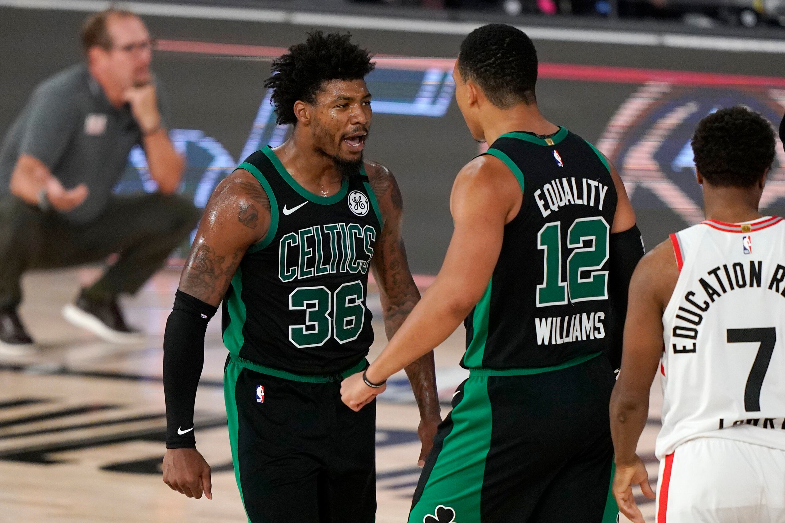 Marcus Smart (36) y Grant Williams, de los Celtics, celebran luego de que Williams colara un importante canasto y recibiera falta durante el encuentro del martes.