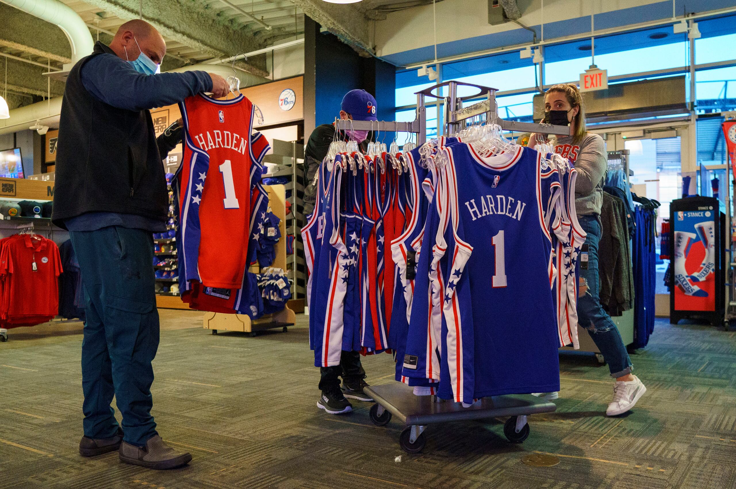 Algunos fanáticos miran las nuevas camisetas de los Sixers de Filadelfia con el nombre y número de James Harden antes del partido ante el Thunder de Oklahoma City el viernes. Harden no jugaría con el equipo hasta la próxima semana.