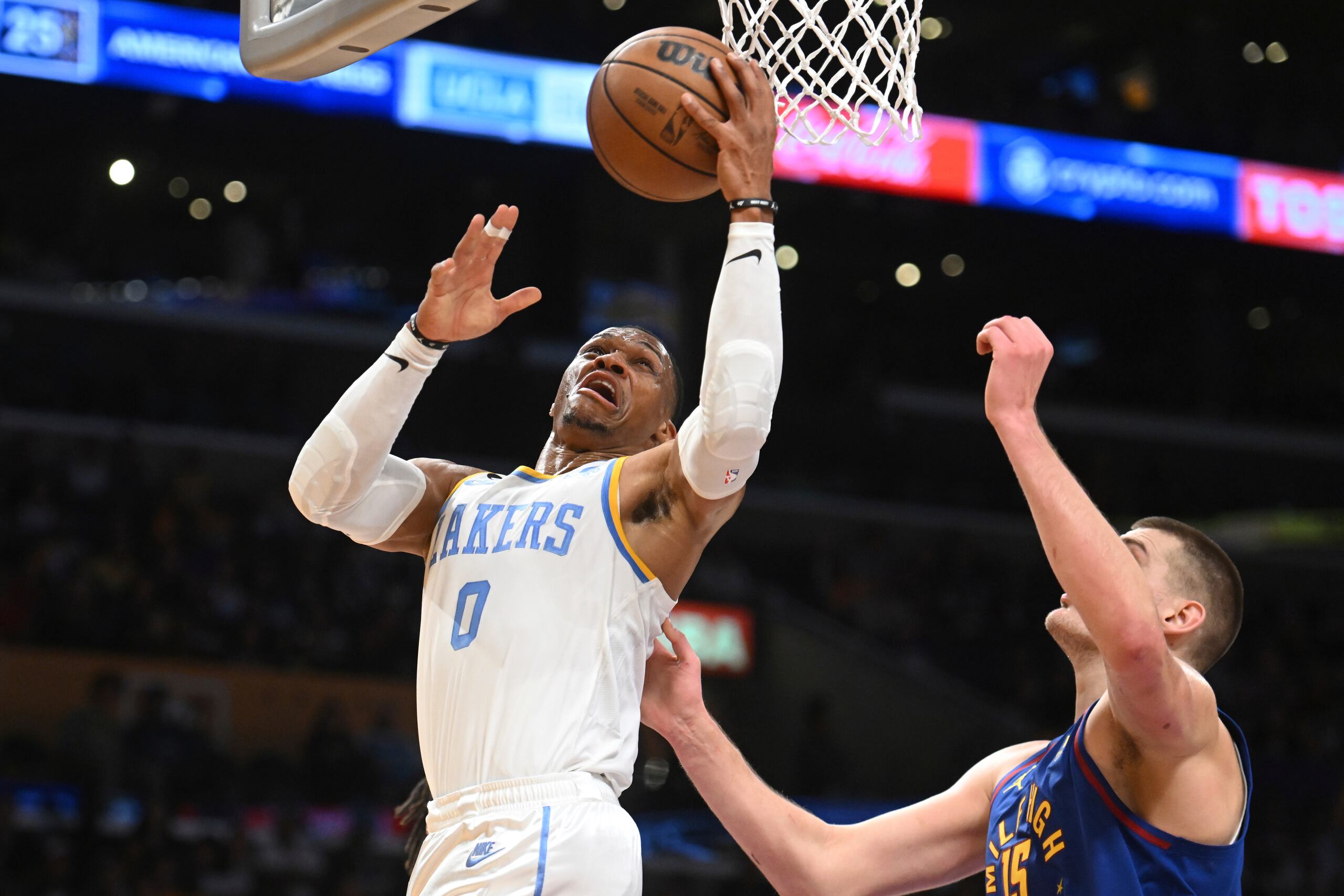 El jugador de los Lakers de Los Ángeles Russell Westbrook (0) salta a canasta contra el jugador de los Nuggets de Denver Nikola Jokic (15) durante la primera mitad de su juego de NBA el domingo 30 de octubre de 2022 en Los Ángeles. (AP Foto/Michael Owen Baker)