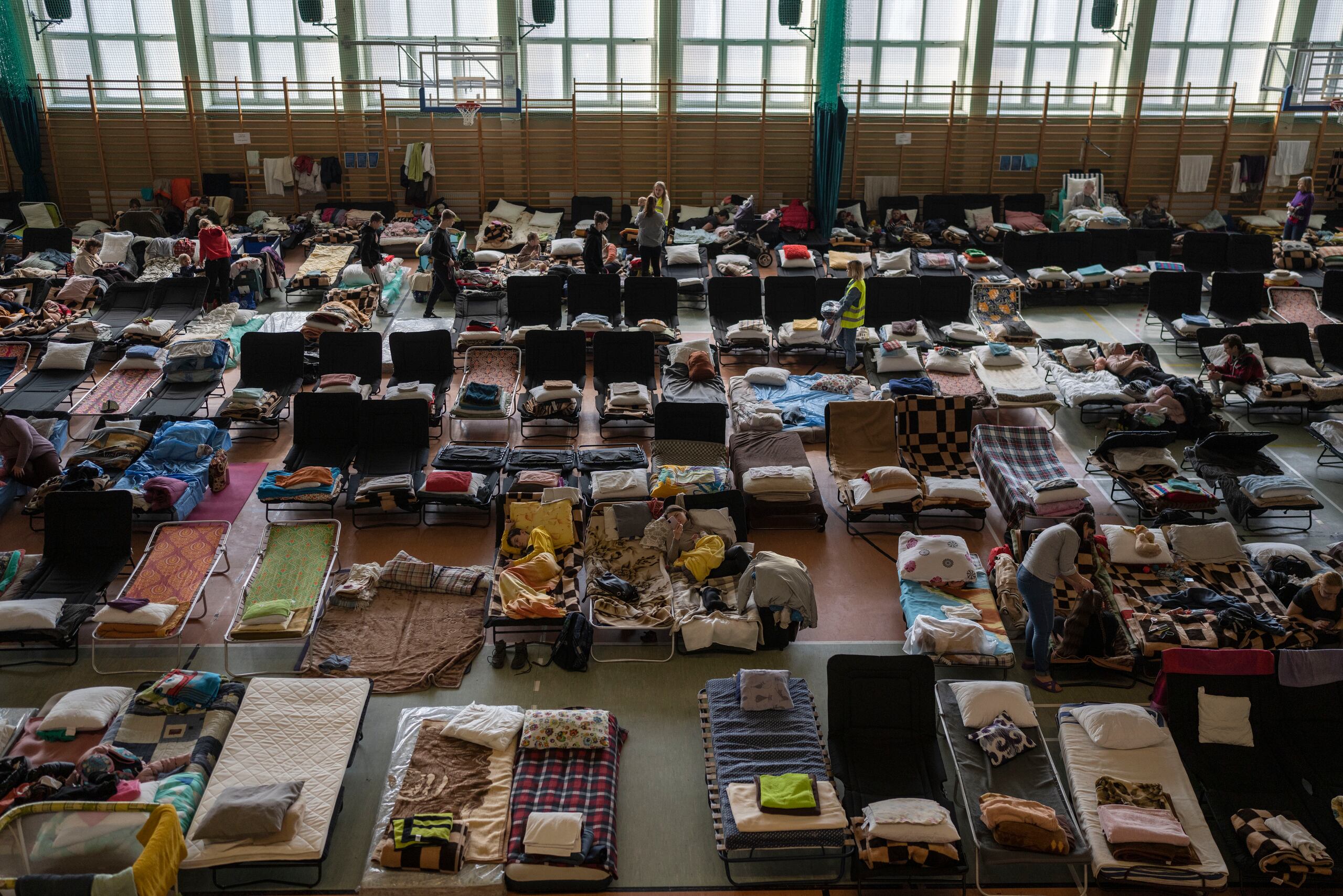 Personas que huyen de la guerra en Ucrania descansan al interior de un estadio deportivo techado usado como centro de refugiados en Medyka, el cruce fronterizo entre Polonia y Ucrania.