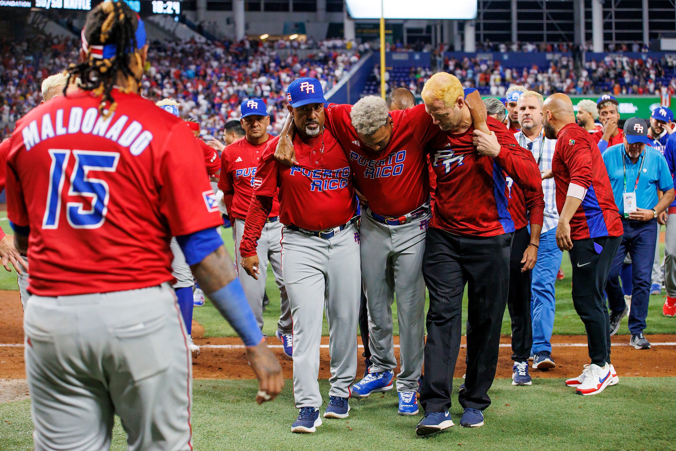 El pitcher puertorriqueño Edwin Díaz (39) recibe auxilio del coach Ricky Bones y el personal médico tras lesionarse en un juego contra la República Dominicana, el miércoles 15 de marzo de 2023, en Miami.