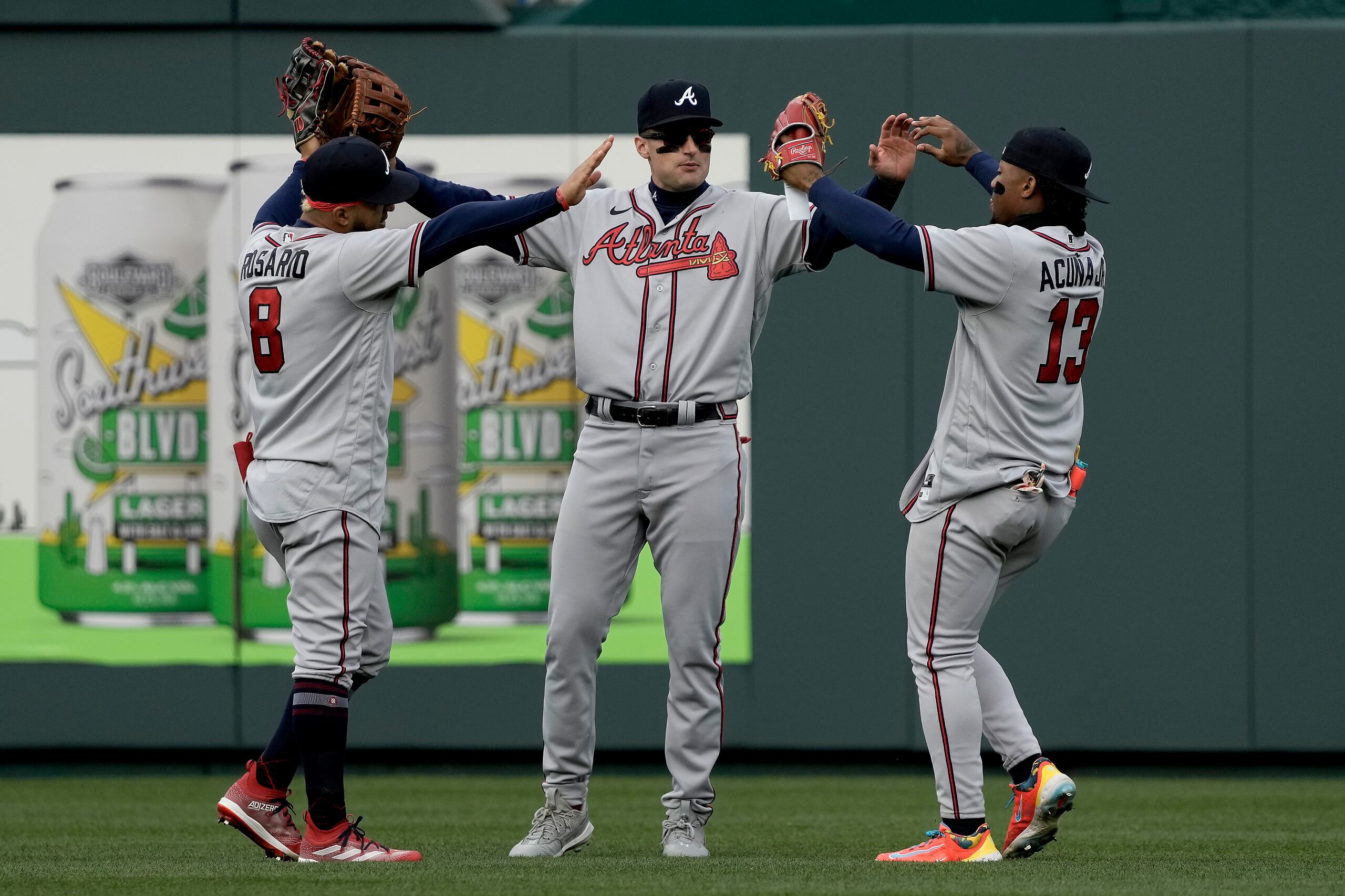 Eddie Rosario (8), Ronald Acuña Jr. (13) y Sam Hilliard, jardineros de los Bravos de Atlanta, celebran la victoria 5-4 ante los Reales de Kansas City, el domingo 16 de abril de 2023, en Kansas City. (AP Foto/Charlie Riedel)