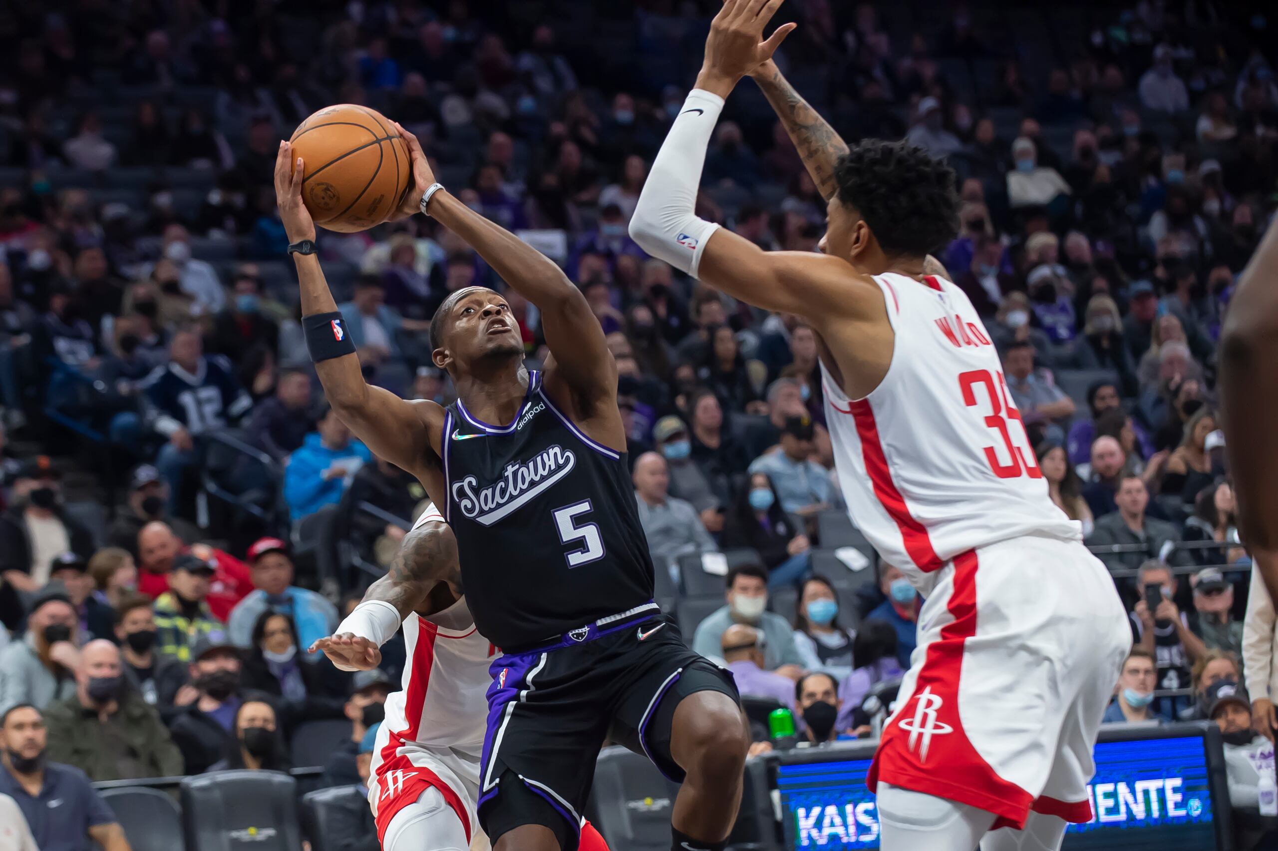 Christian Wood, de los Rockets de Houston, intenta impedir la ofensiva de De'Aaron Fox, de los Kings de Sacramento, que anoche anotó 27 tantos.