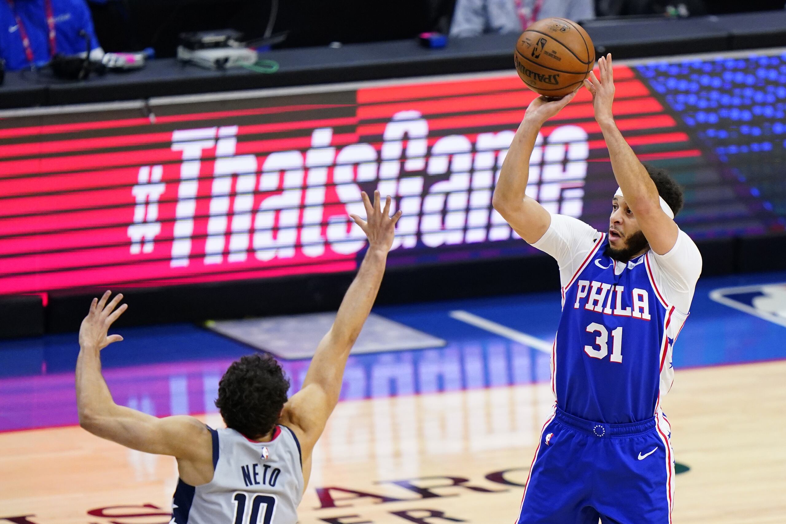 Seth Curry de los 76ers de Filadelfia tira el balón superando a Raúl Neto de los Wizards de Washington en el juego 5 de la serie de primera ronda de postemporada.