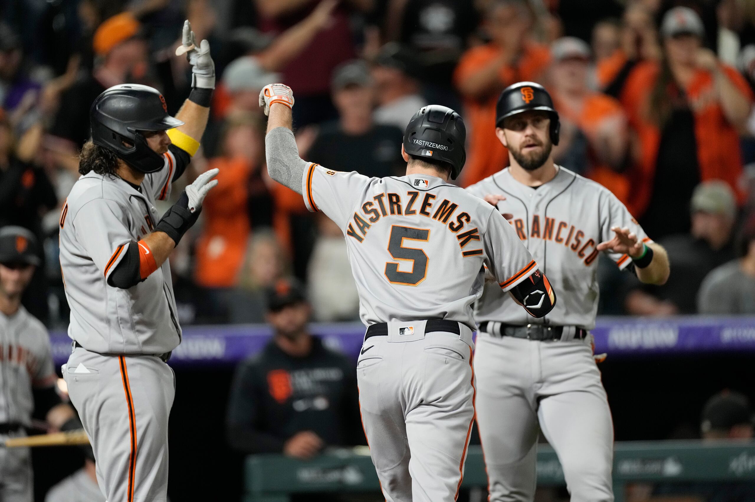 Mike Yastrzemski es felicitado por sus compañeros Brandon Crawford (izquierda) y Evan Longoria, luego de pegar un jonrón de tres carreras en el duelo ante los Rockies de Colorado.