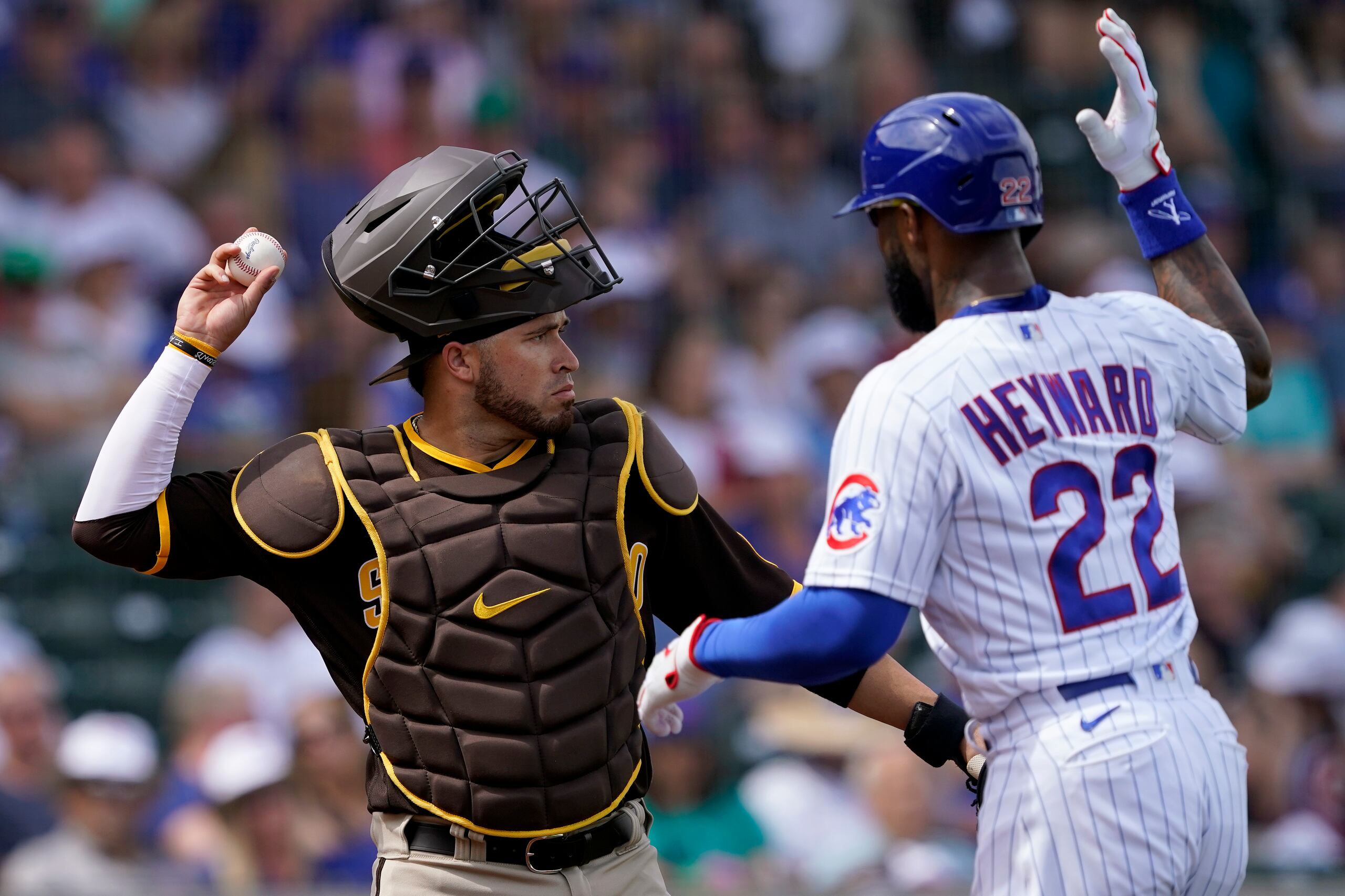 Jason Hayward de los Cachorros de Chicago bromea intentando bloquear el tiro del catcher Victor Caratini de los Padres de San Diego el 19 de marzo del 2022. (AP Foto/Matt York)