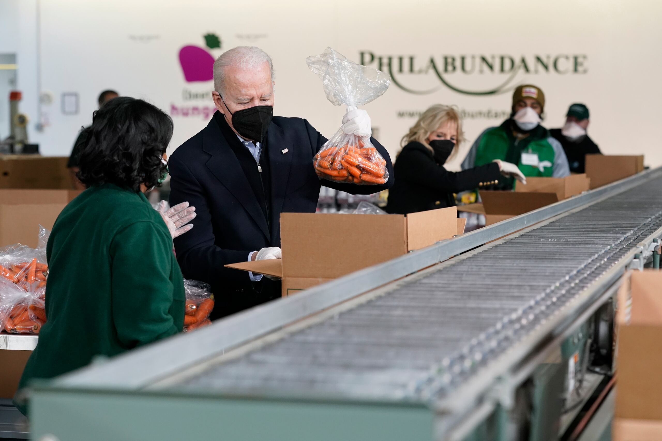 El presidente Joe Biden y la primera dama Jill Biden empacan zanahorias y manzanas el domingo en el banco de alimentos Philabundance, el 16 de enero de 2022, en Filadelfia.