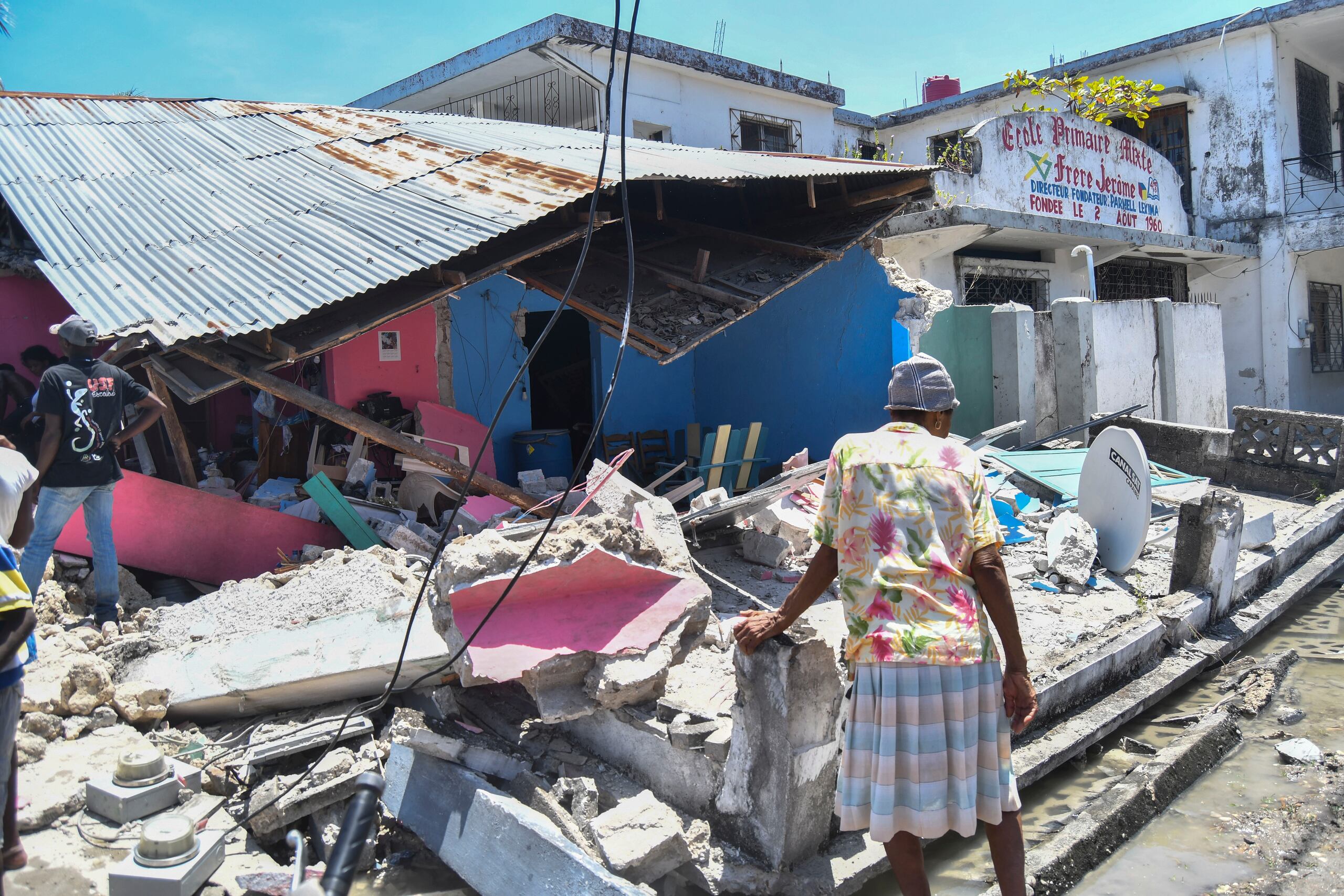 Una mujer se para frente a una casa destruida después de un terremoto en Les Cayes, Haití.