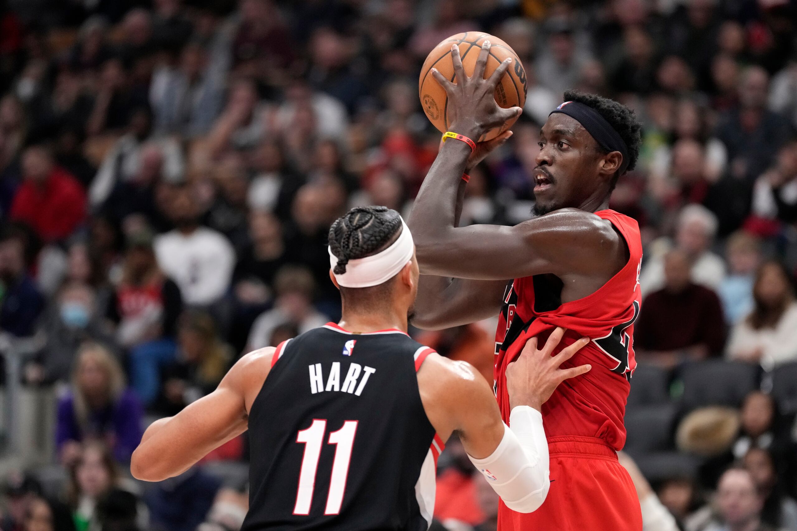 Pascal Siakam, derecha, de los Raptors de Toronto, busca mandar un pase ante la presión de Josh Hart (11), de los Blazers de Portland, durante la segunda mitad del juego de baloncesto de la NBA en Toronto, el domingo 8 de enero de 2023. (Frank Gunn/The Canadian Press vía AP)