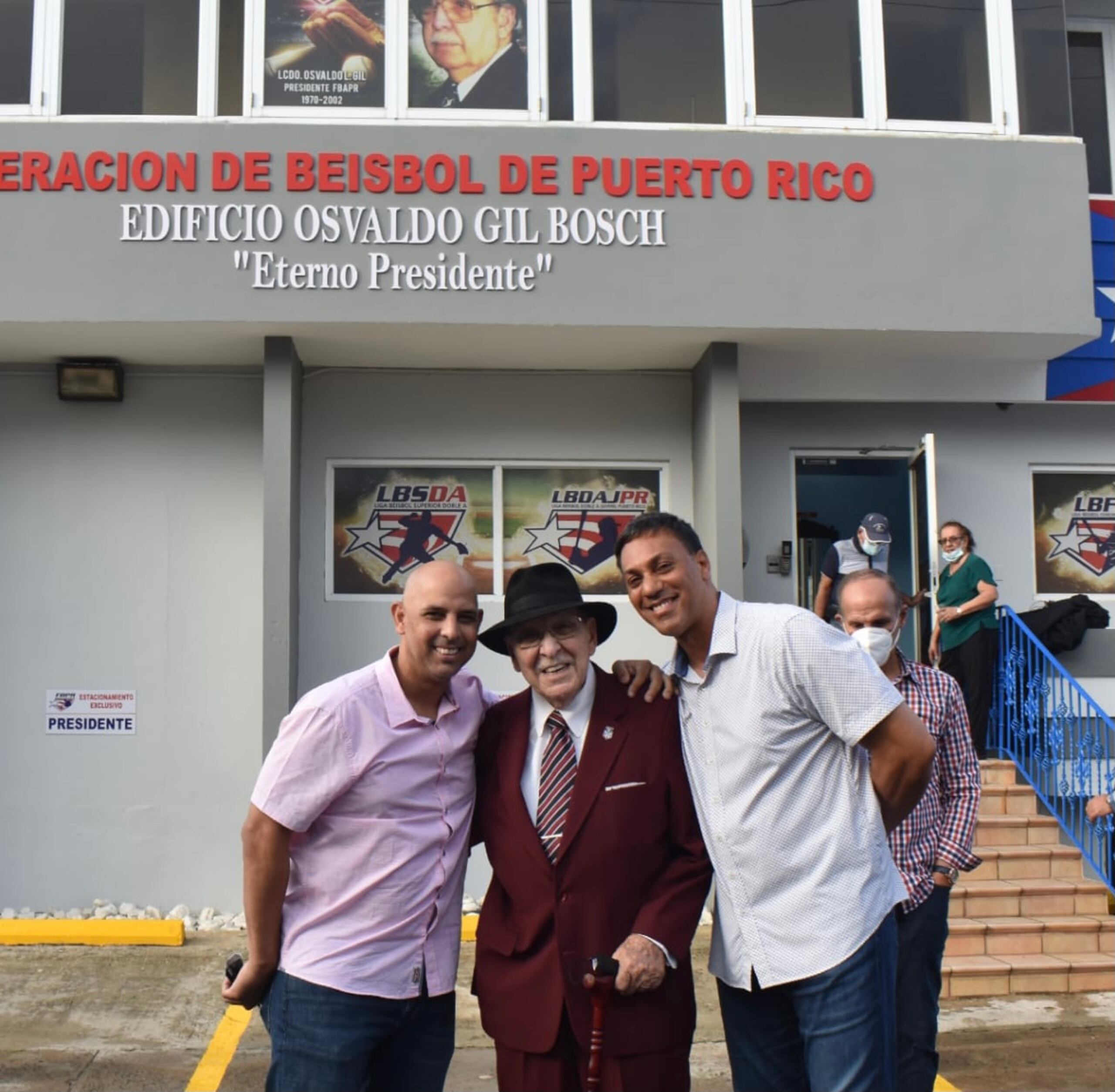 Alex Cora y Juan "Igor" González, respectivamente a la izquierda y derecha en la foto, posan junto al Lic. Osvaldo Gil Bosch frente al edificio que alberga la Federación de Béisbol de Puerto Rico y que quedó bautizado a su nombre este pasado sábado.