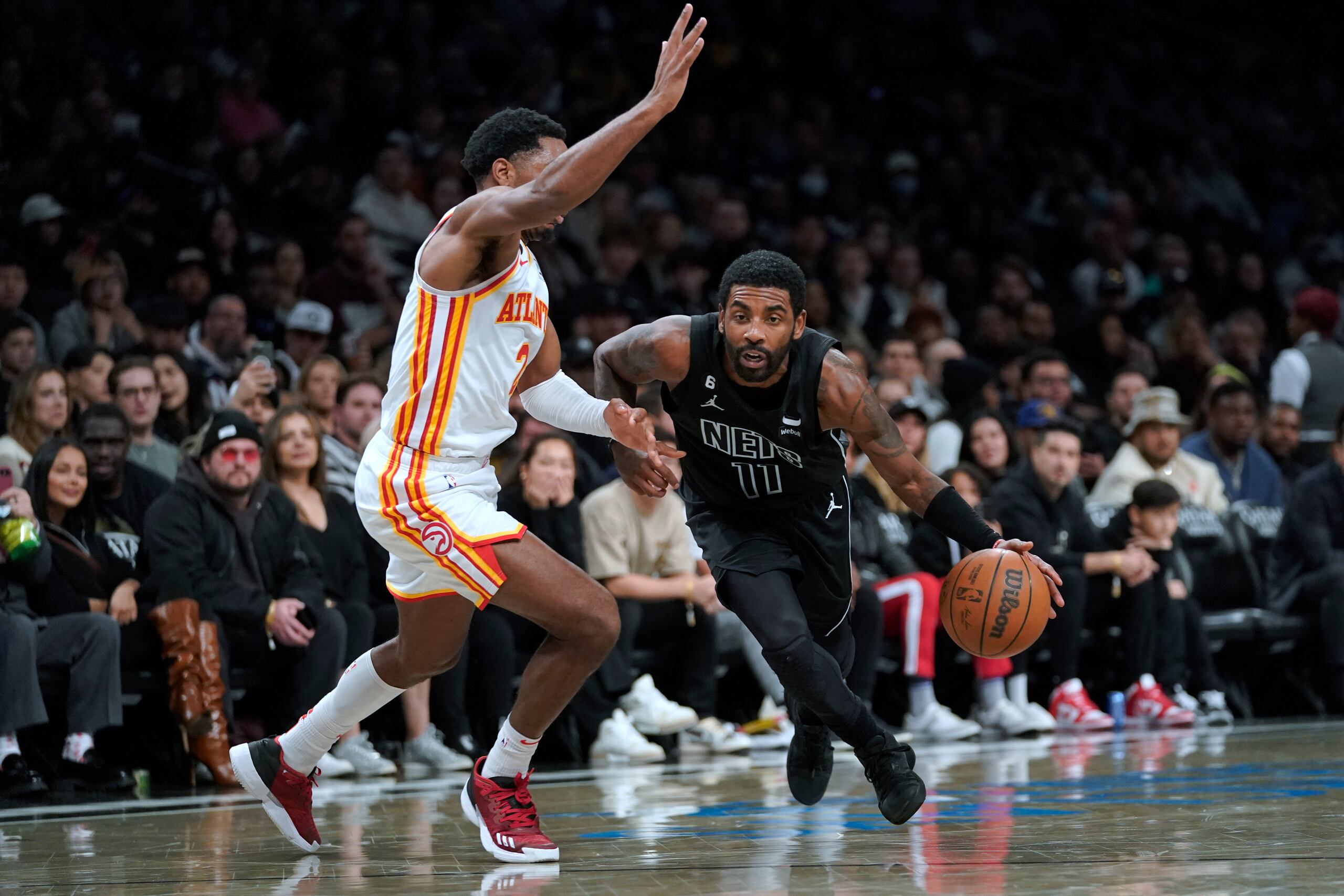 Kyrie Irving (11), de los Nets de Brooklyn, conduce el balón frente a la marca de Trent Forrest (2), de los Hawks de Atlanta.