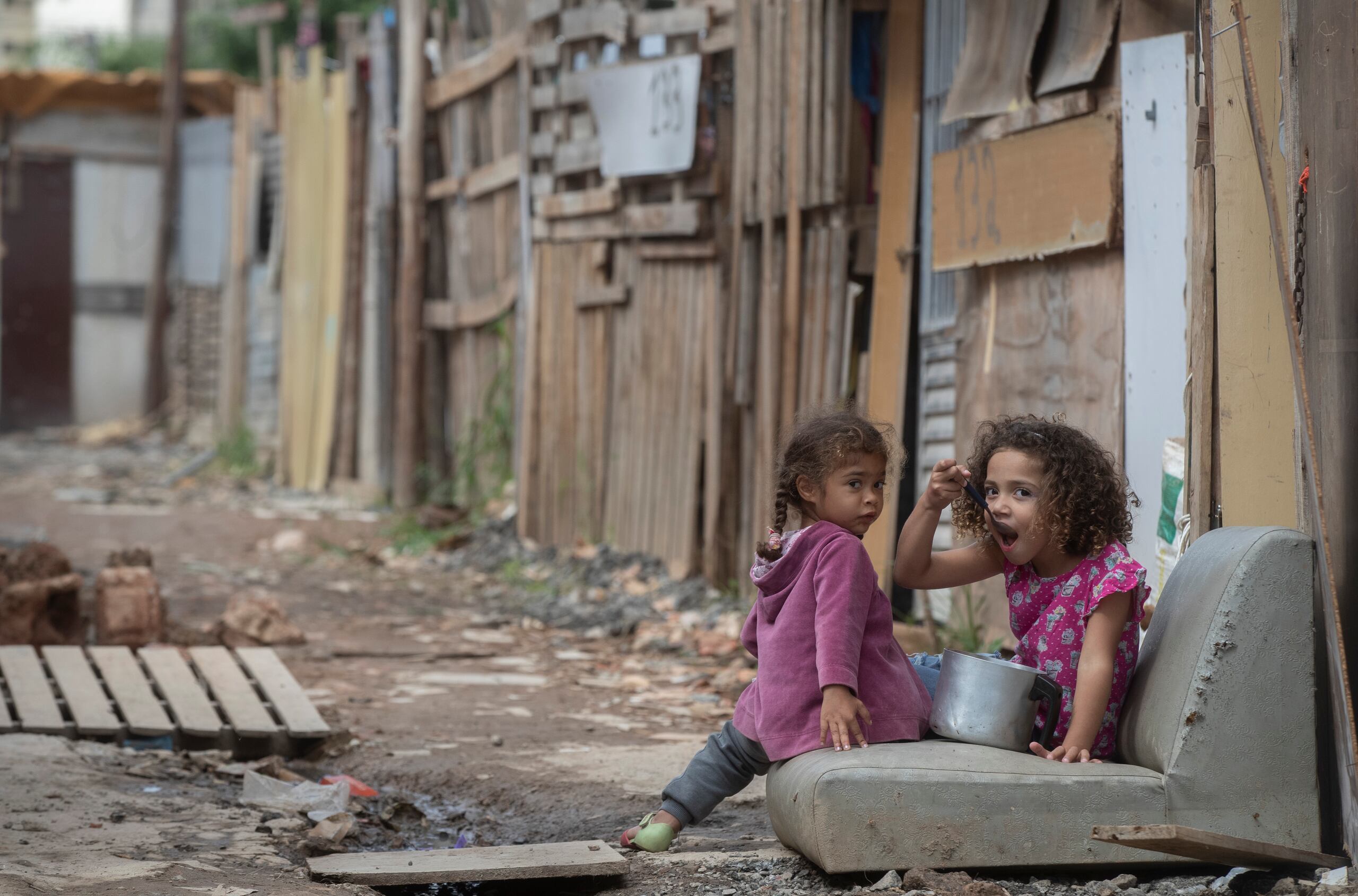 Una niña come de una cacerola en la calle en la favela Penha Brasil en Sao Paulo.