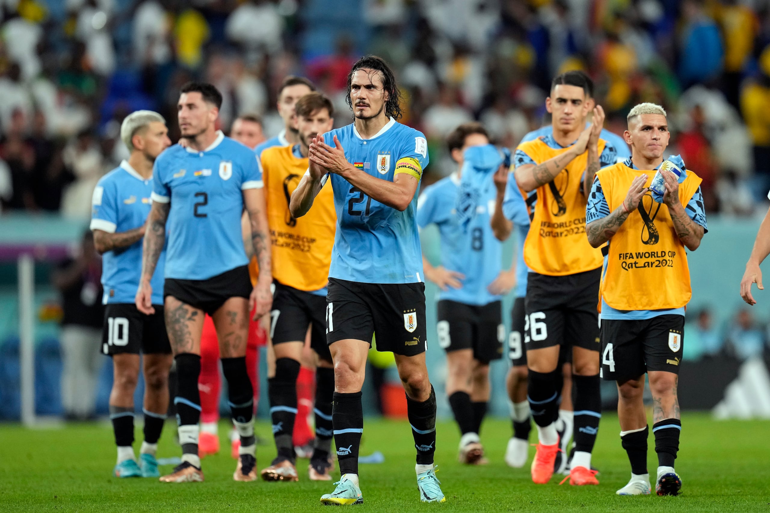 Liderados por Edinson Cavani (21), los jugadores de Uruguay agradecen al público mientras salen del terreno tras conocer que habían quedado eliminados del Mundial de Qatar pese a su triunfo.