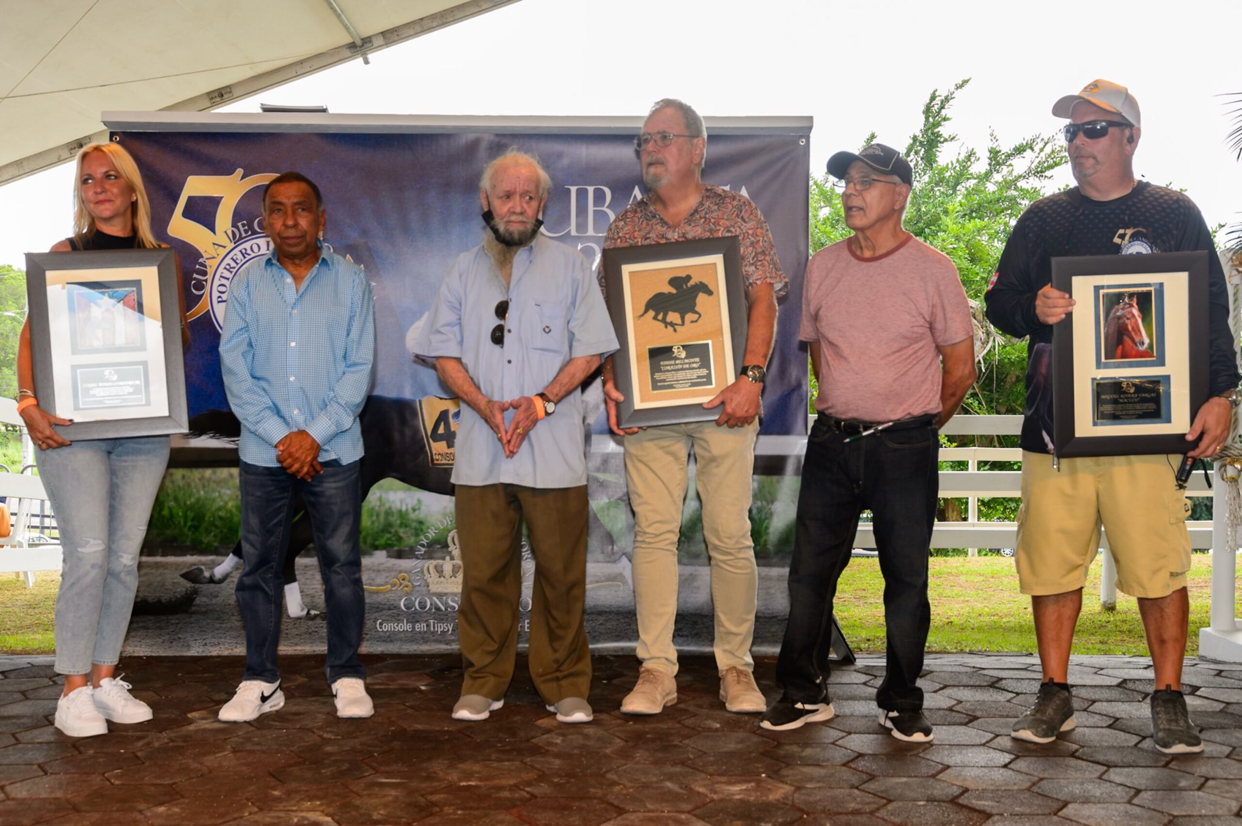 La familia Maldonado del potrero Los Llanos sostiene las placas con que honraron a los tres jinetes leyendas de Puerto Rico, Ángel 'Junior' Cordero, Eddie Belmonte y Miguel A. Rivera 'Macuco' en el 50 aniversario de la subasta del potrero coameño.