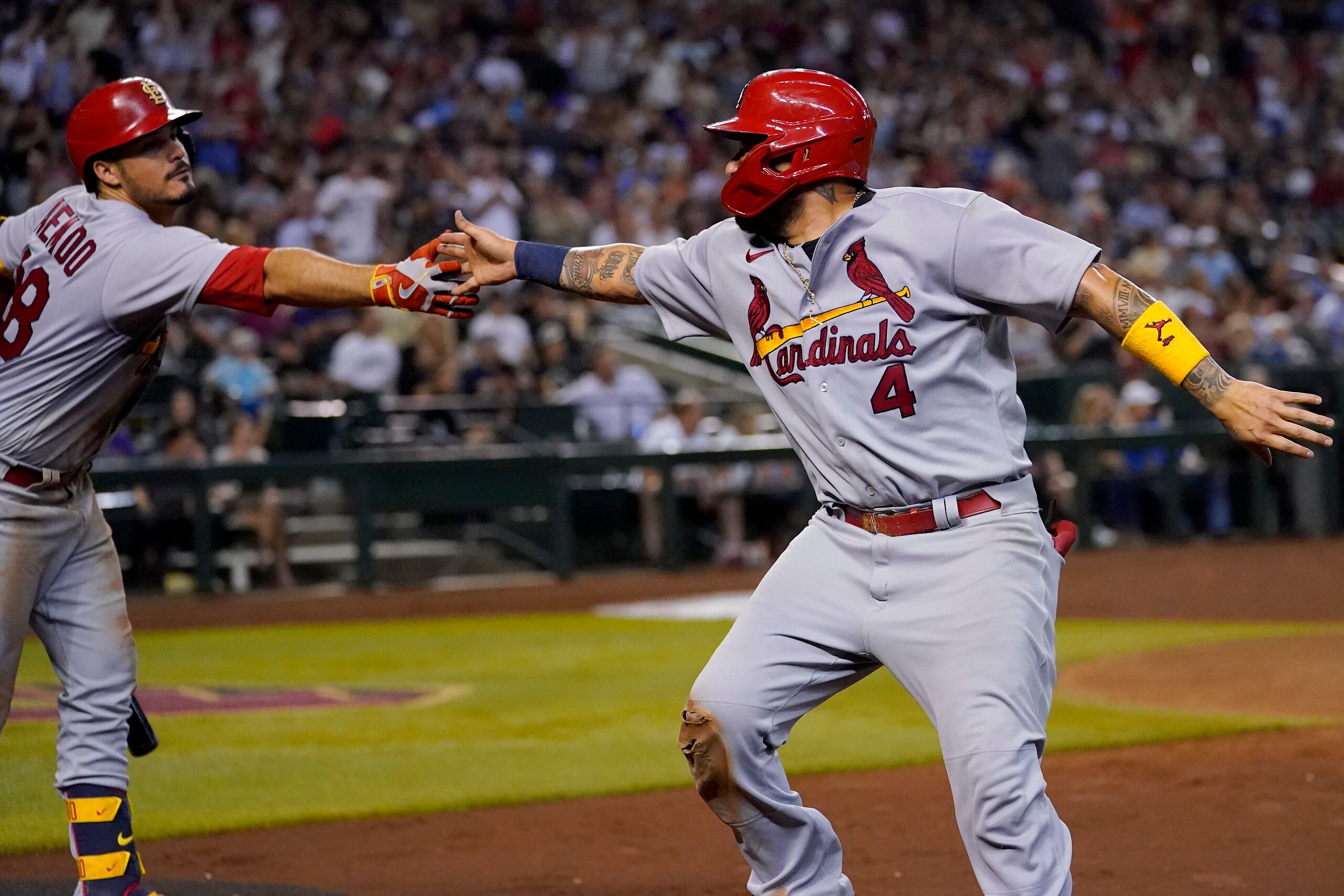 El boricua Yadier Molina (4), de los Cardenales de San Luis, festeja con Nolan Arenado, tras anotar ante los Diamondbacks de Arizona, el viernes 19 de agosto de 2022.