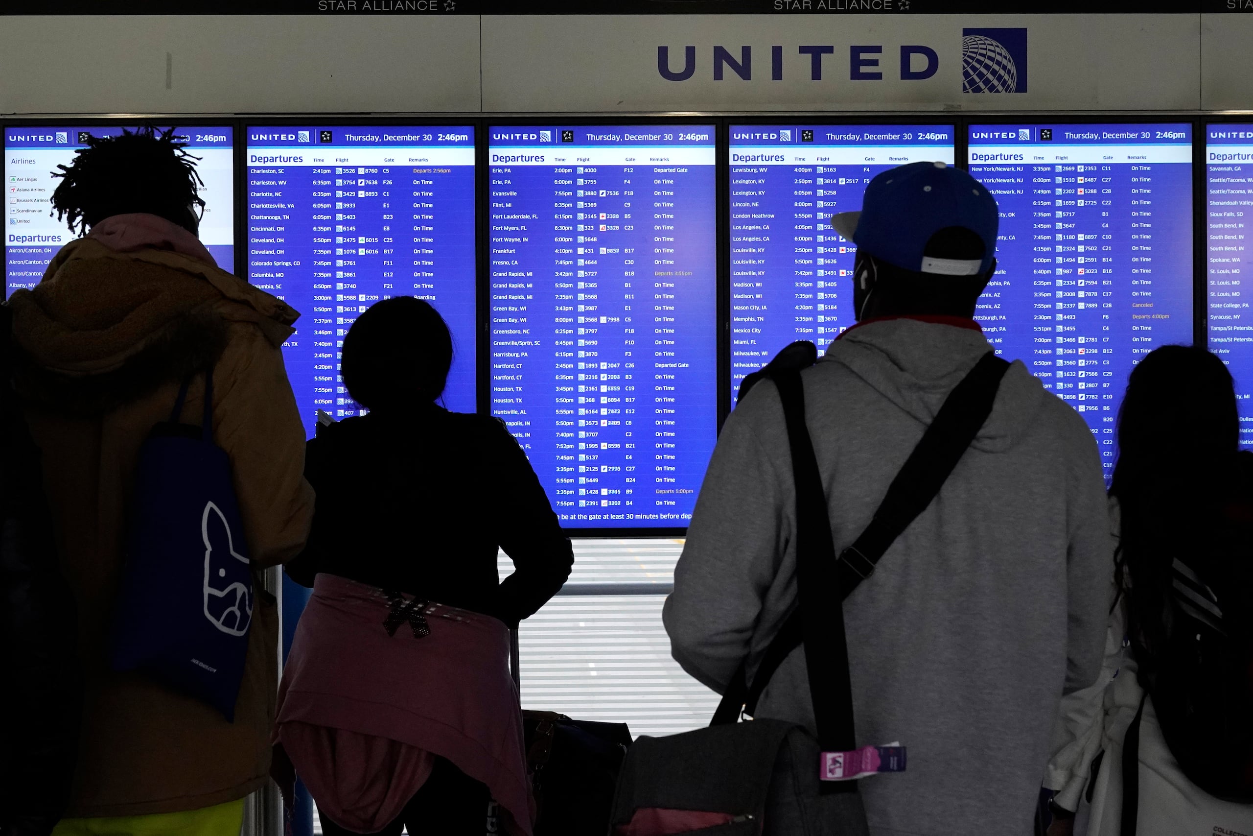 Viajeros revisan pantallas para checar el estatus de su vuelo en el Aeropuerto Internacional O'Hare en Chicago, el jueves 30 de diciembre de 2021. (AP Foto/Nam Y. Huh)