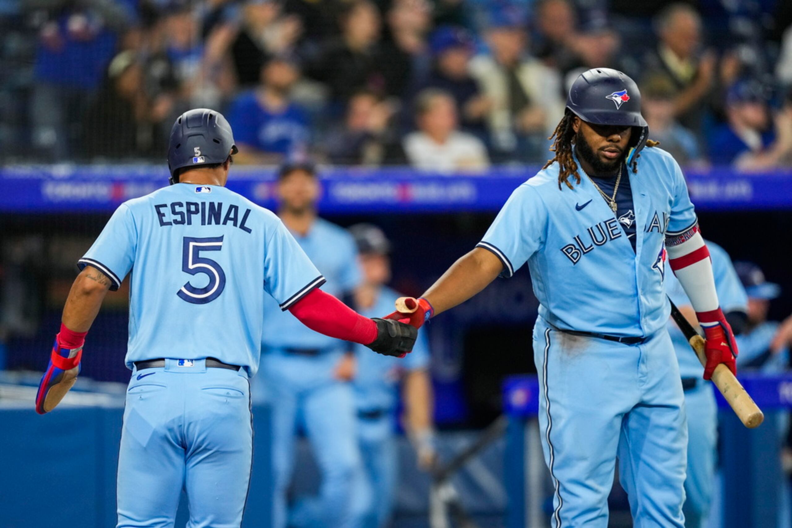 Santiago Espinal celebra con su compañero Vladimir Guerrero Jr. tras anotar una carrera.