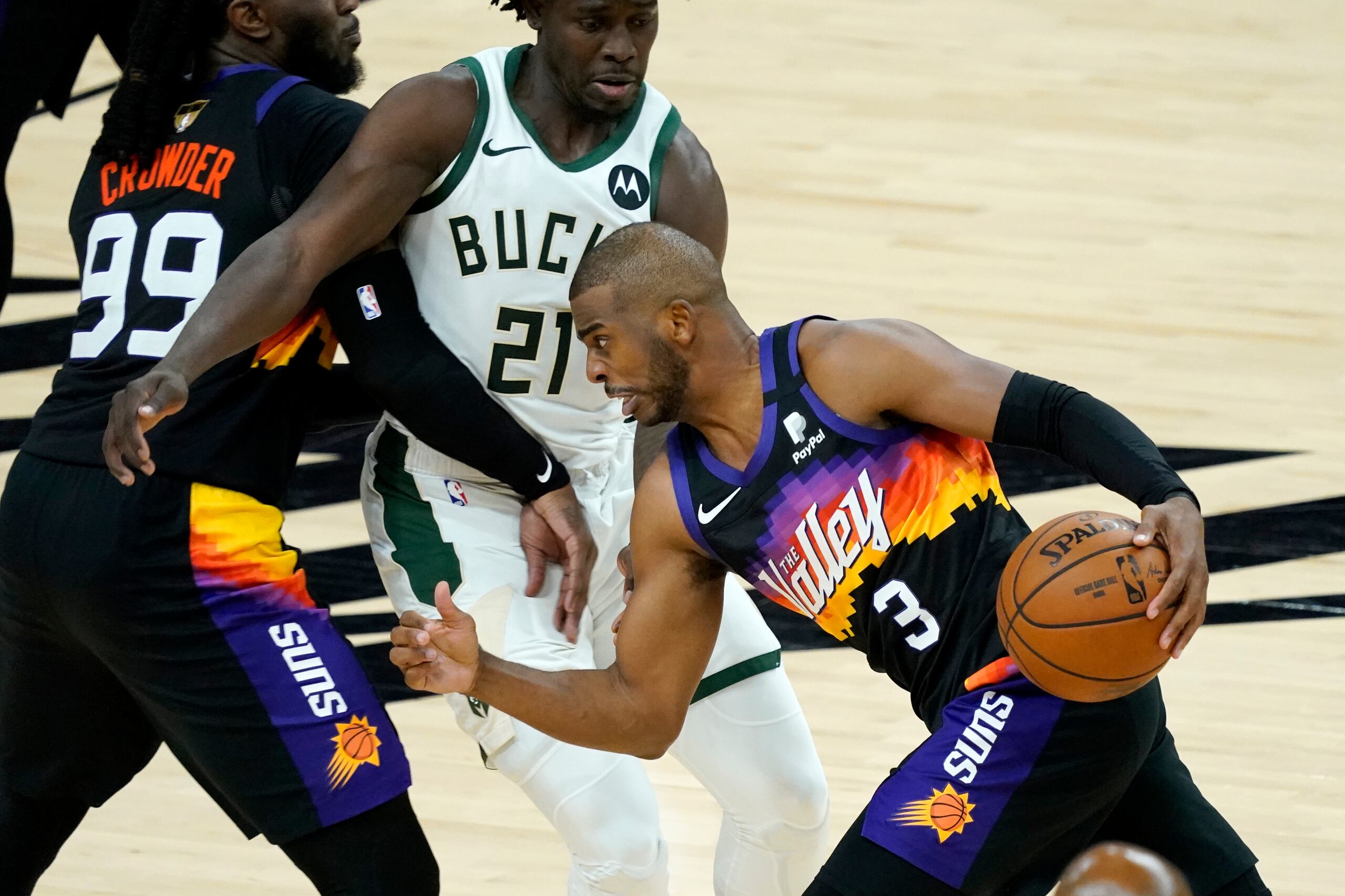 Chris Paul (3), armador de los Suns de Phoenix, se libera de la defensa de Jrue Holiday (21), de Milwaukee, en una cortina durante el desafío del martes.