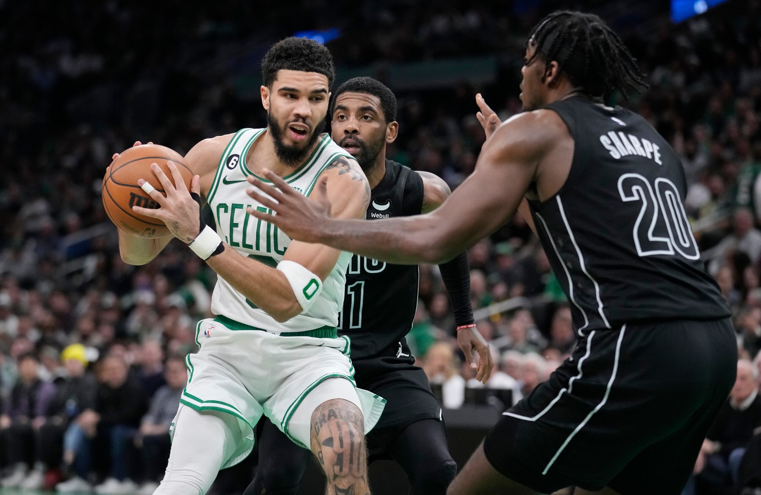 Jayson Tatum, de los Celtics de Boston, intenta pasar entre Day'ron Sharpe y Kyrie Irving, de los Nets de Brooklyn, durante el partido del miércoles.