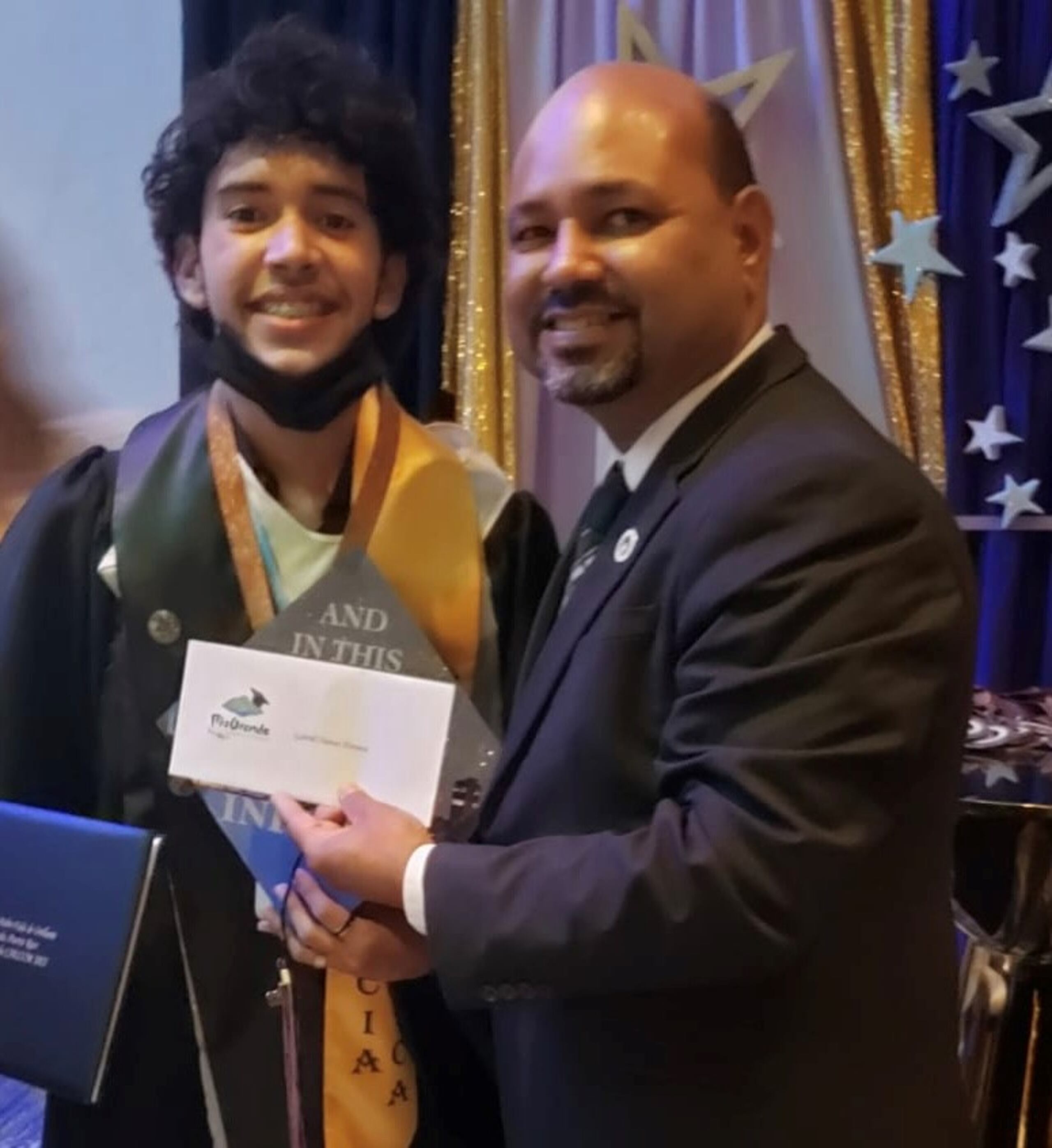 El alcalde de Río Grande, Ángel González Damudt, entrega incentivo a un graduando de escuela superior.