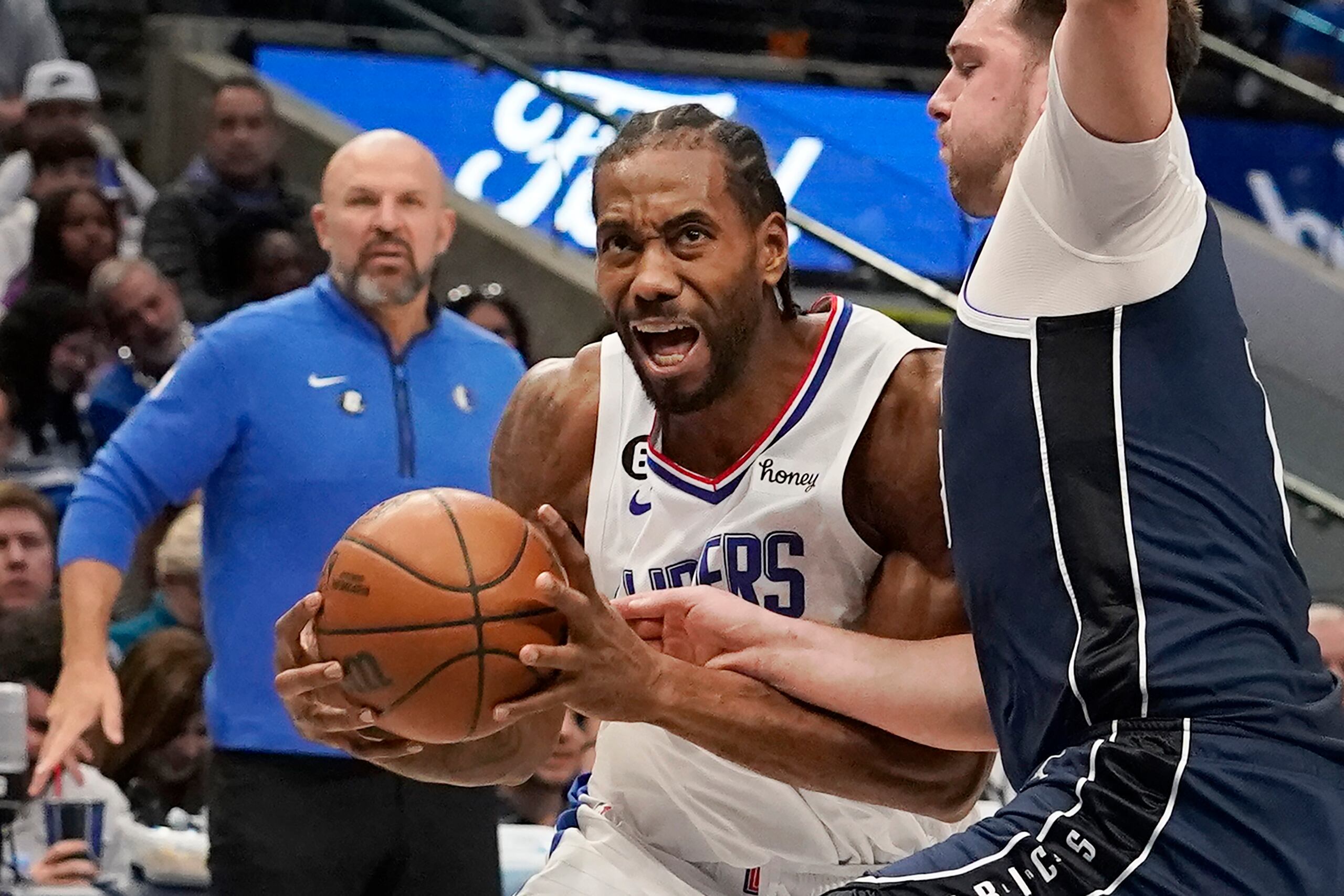 Kawhi Leonard, alero de los Clippers de Los Ángeles, controla el balón y ataca la canasta mientras Luka Doncic, de los Mavericks de Dallas, defiende, ante la mirada del coach Jason Kidd, al fondo, durante la primera mitad del juego de baloncesto de la NBA, en Dallas, el domingo 22 de enero de 2023. (AP Foto/LM Otero)