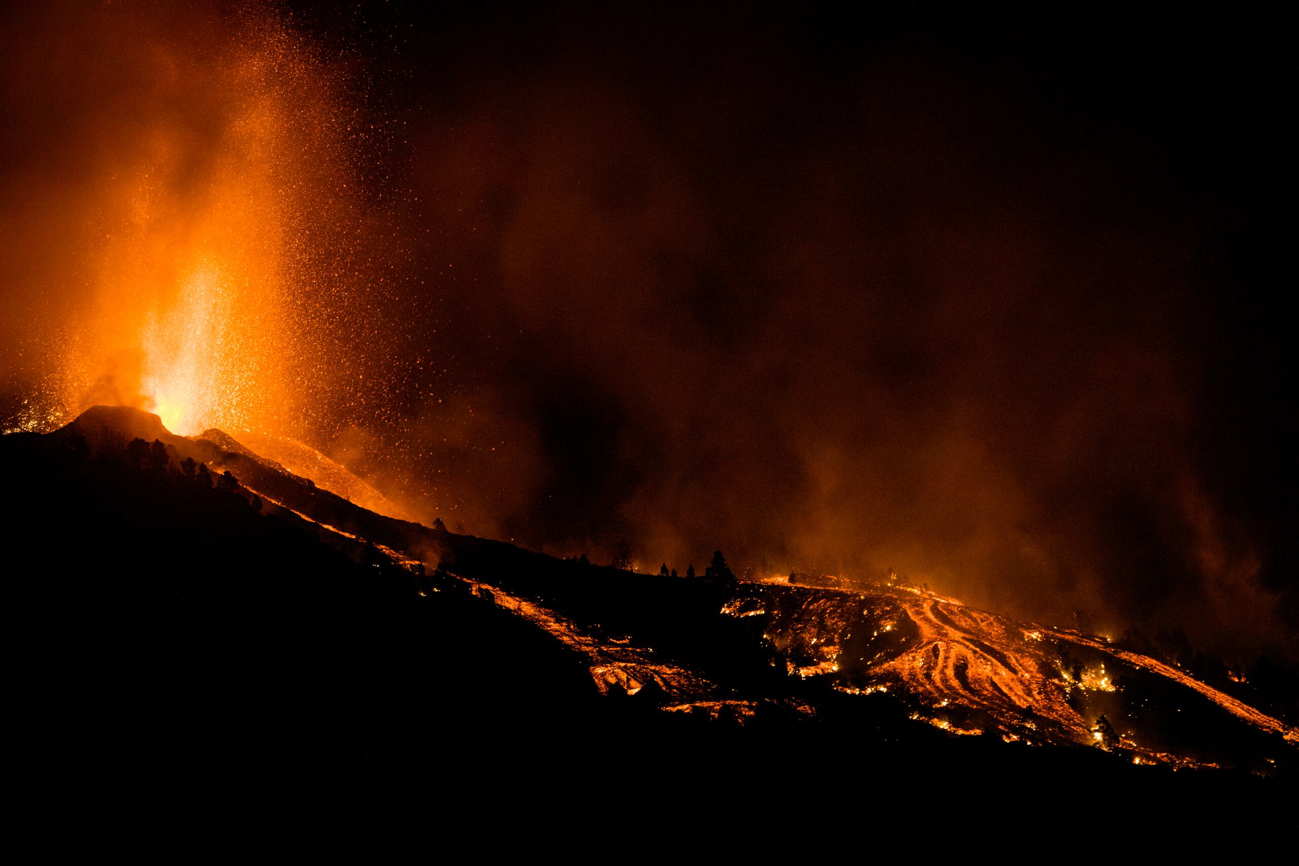 Lava flows from an eruption of a volcano at the island of La Palma in the Canaries, Spain, Sunday, Sept. 19, 2021. A volcano on Spain's Atlantic Ocean island of La Palma erupted Sunday after a weeklong buildup of seismic activity, prompting authorities to evacuate thousands as lava flows destroyed isolated houses and threatened to reach the coast. New eruptions continued into the night. (AP Photo/Jonathan Rodriguez)