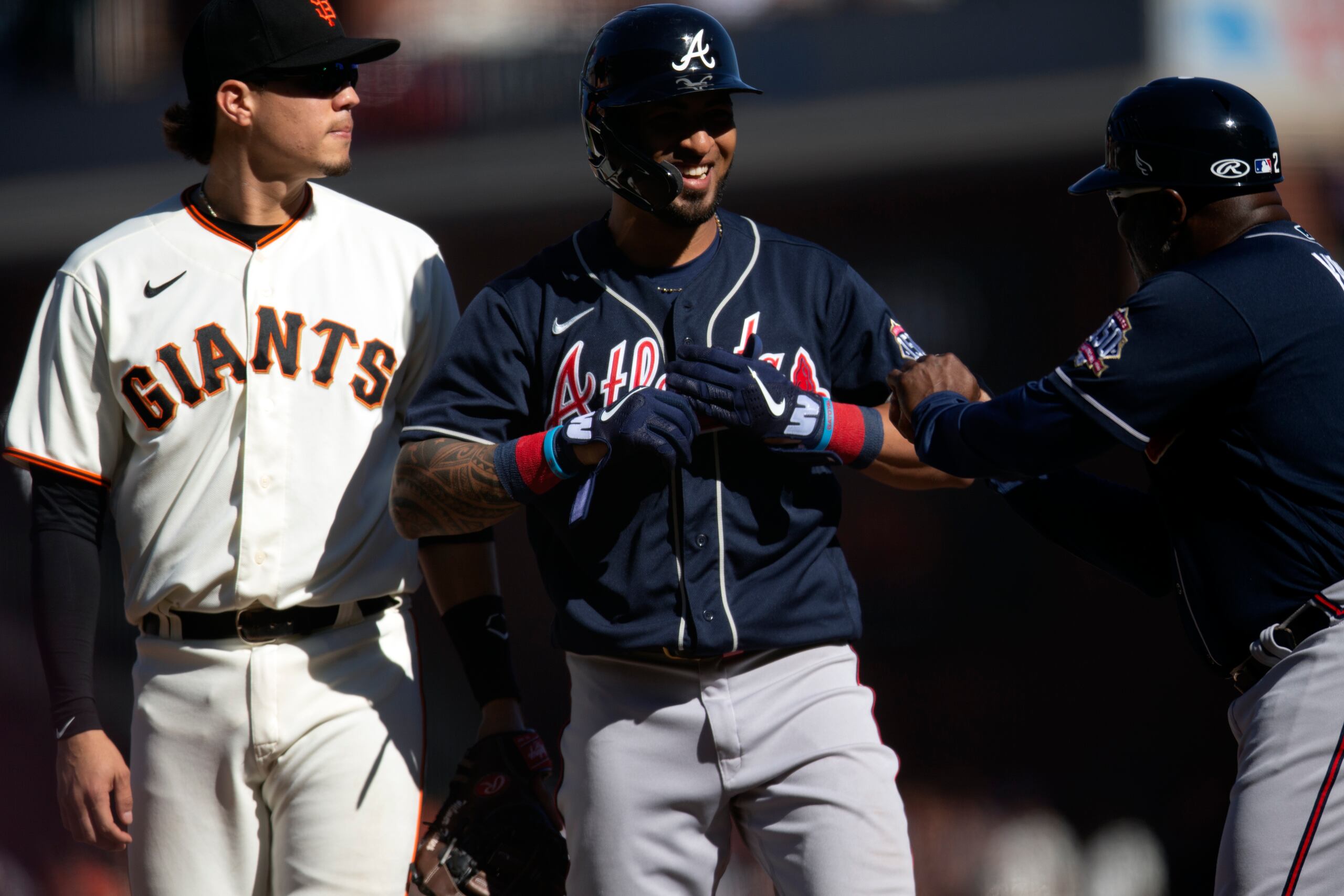 El coach de los Braves, Eric Young, felicita a Eddie Rosario luego de completar el ciclo en la novena entrada. 