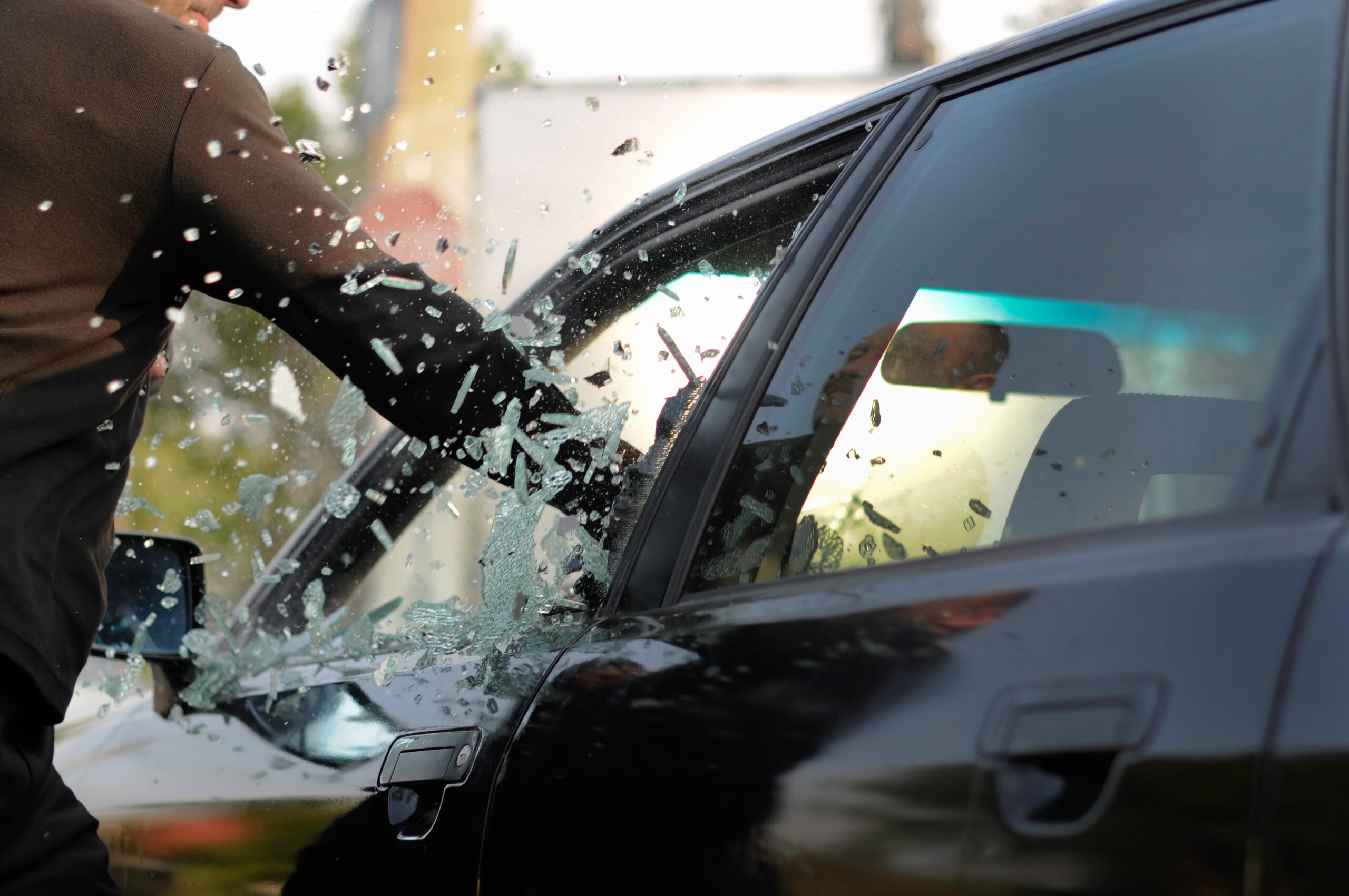 Simulación de un hombre que rompe el cristal de un carro para robar.